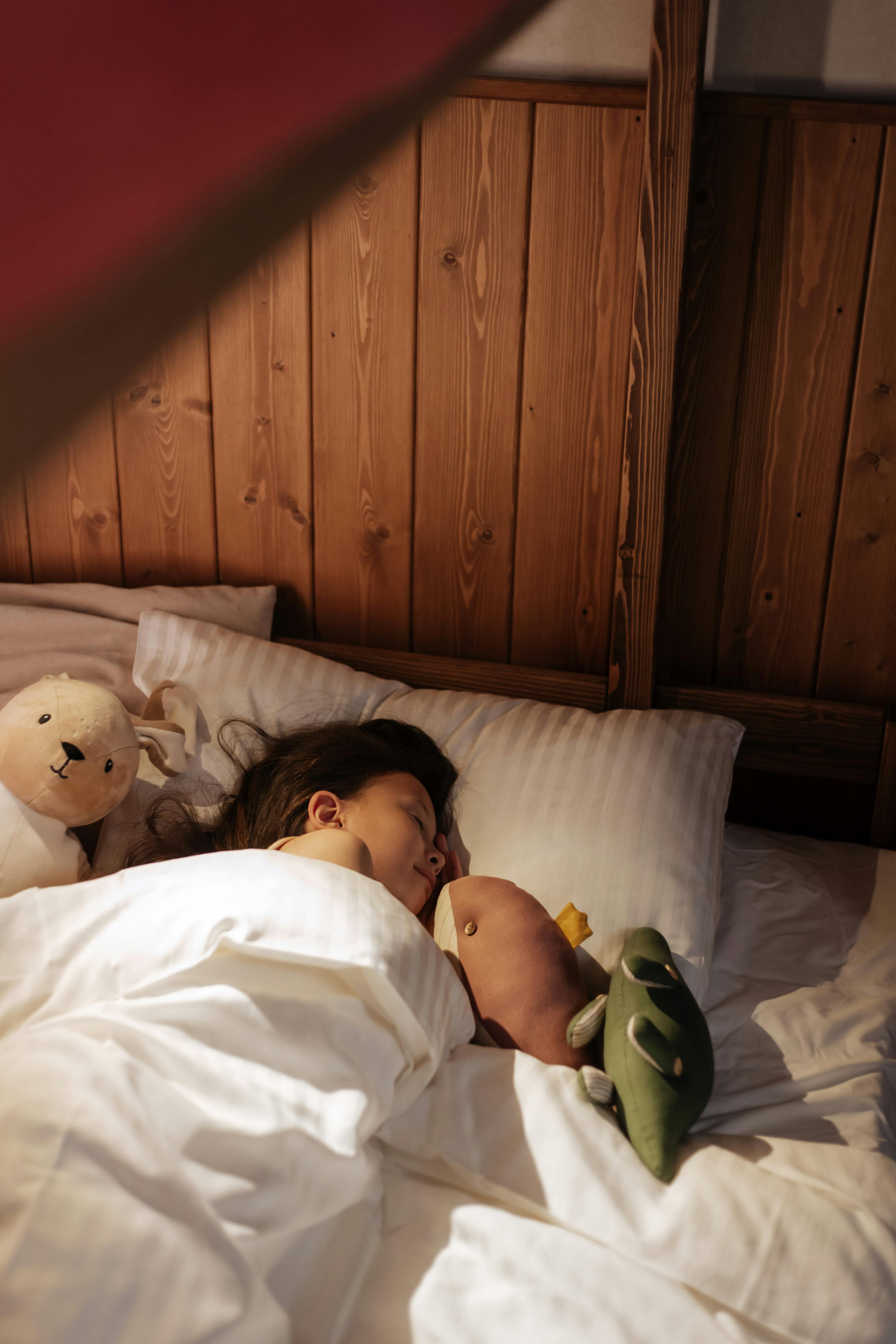 Une petite fille qui dort avec ses peluches | Source : Pexels