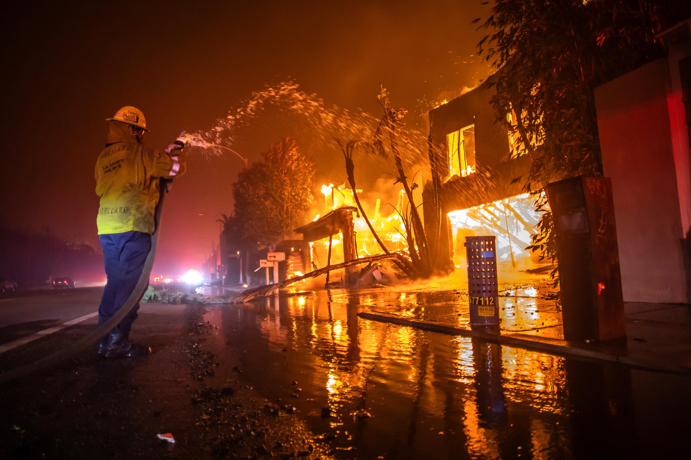 Un pompier lutte contre l'incendie de Palisades alors qu'il brûle des maisons sur Pacific Coast Highway au milieu d'une puissante tempête de vent à Los Angeles, Californie, le 8 janvier 2025 | Source : Getty Images