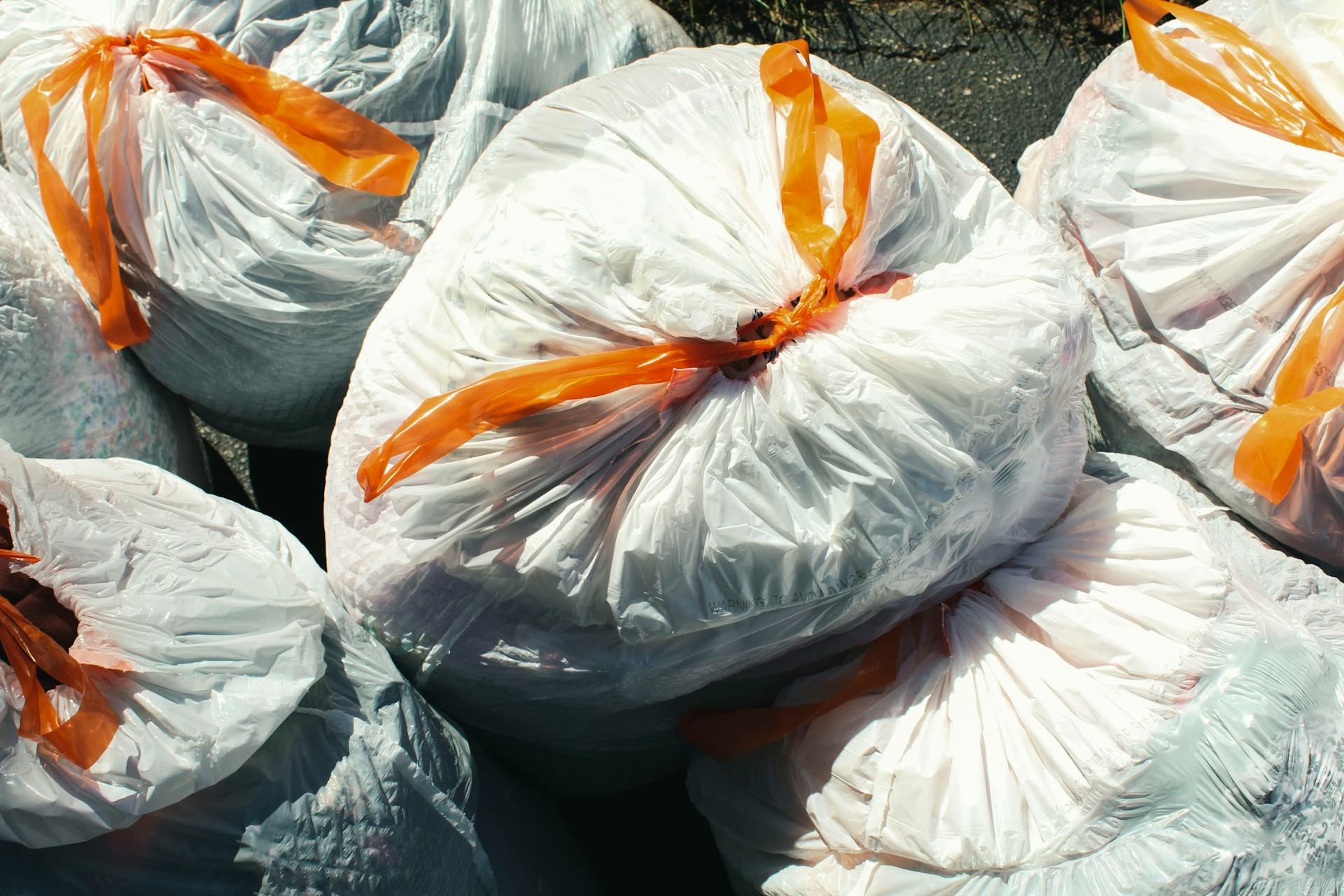 Plusieurs sacs poubelles attachés avec un ruban orange | Source : Pexels