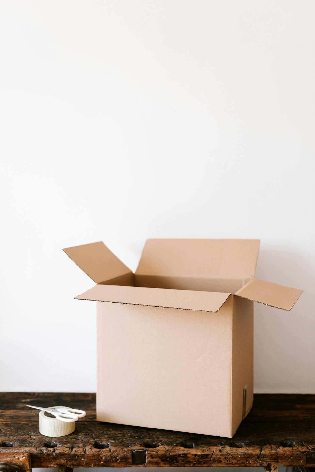 Une paire de ciseaux, du ruban adhésif et une boîte en carton sur une table | Source : Pexels