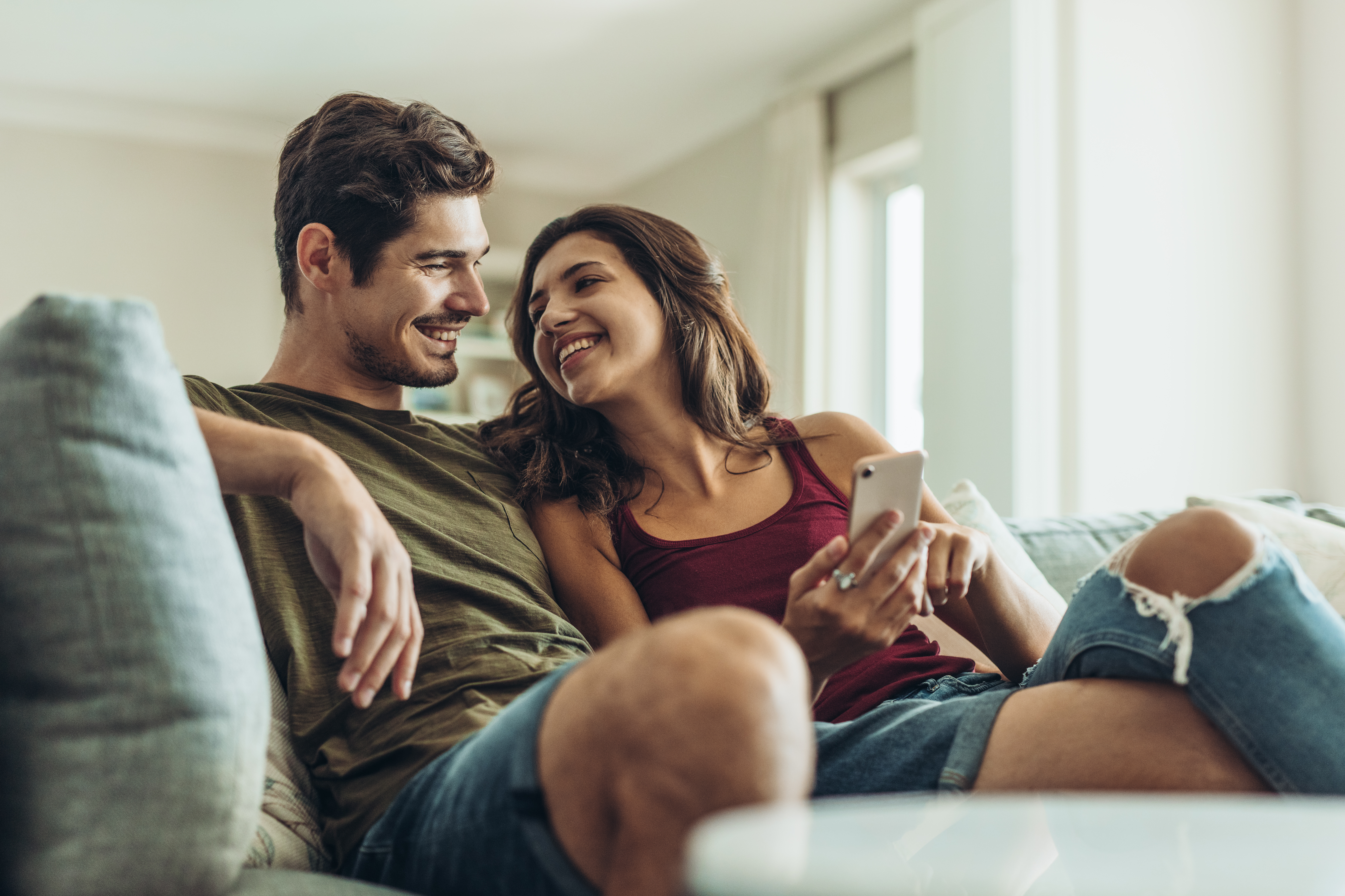 Un couple heureux qui se sourit sur le canapé | Source : Shutterstock