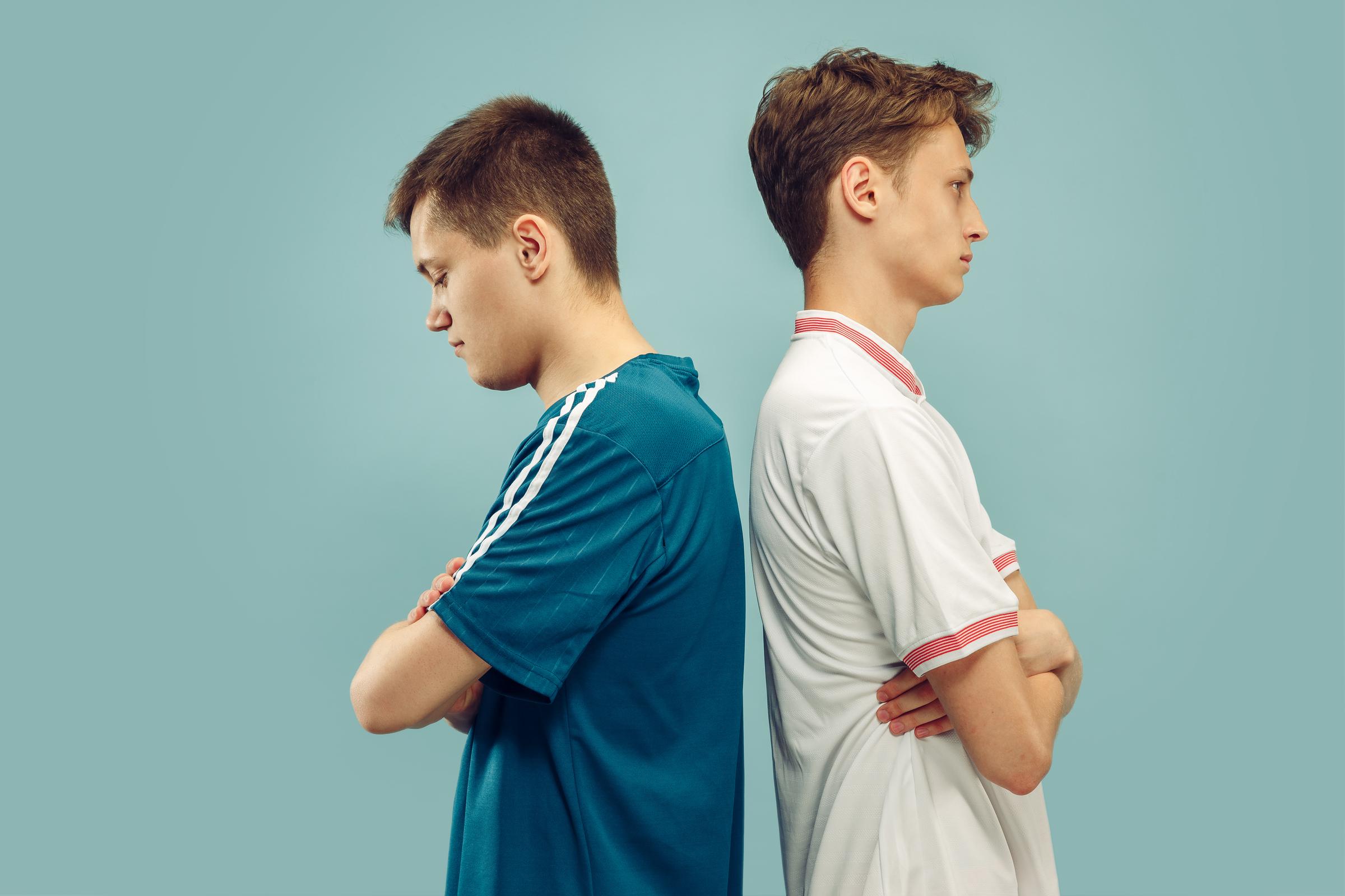 Deux jeunes hommes debout, le dos tourné l'un vers l'autre | Source : Freepik