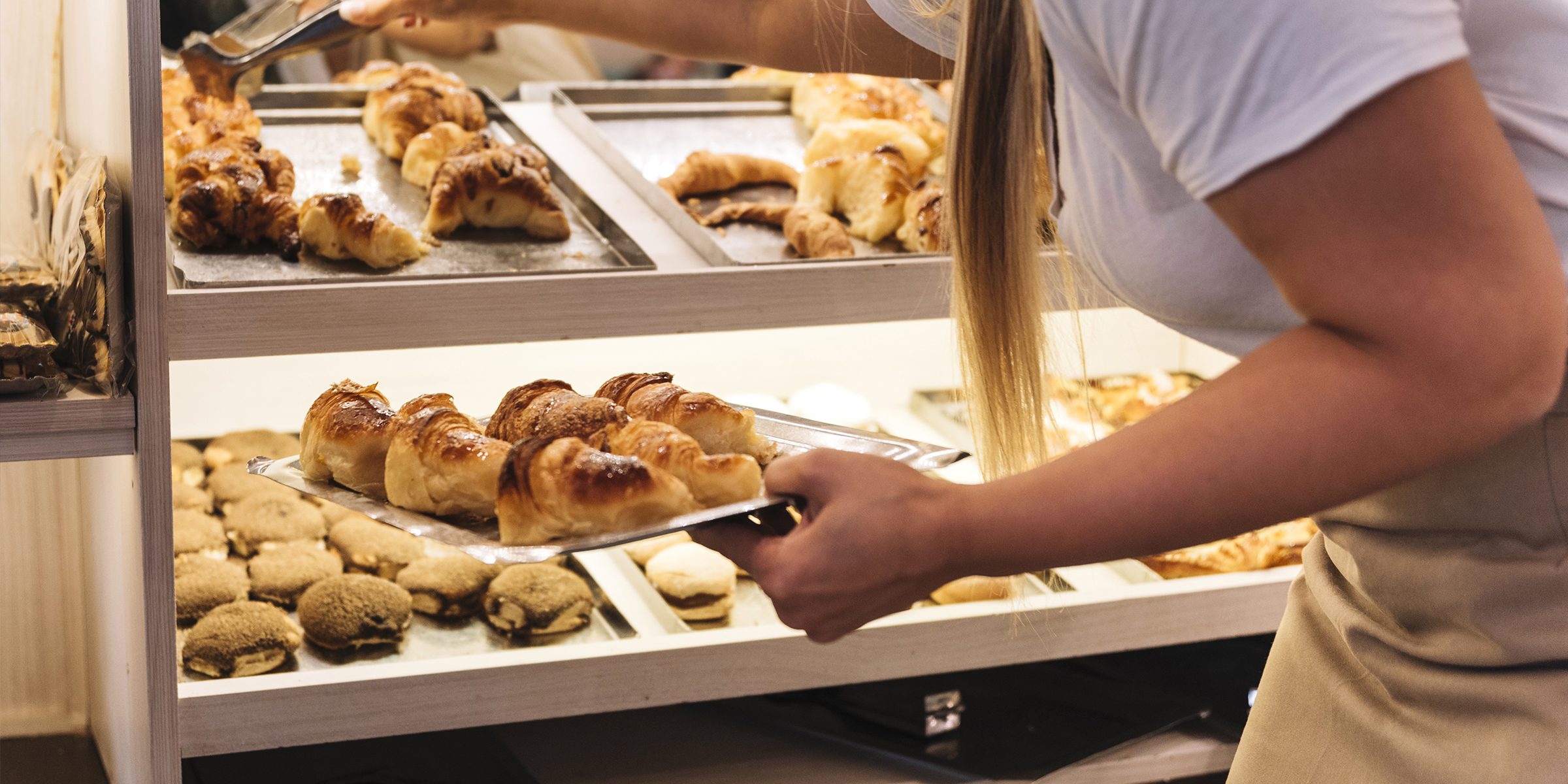 Une femme qui approvisionne une vitrine de boulangerie | Source : Freepik