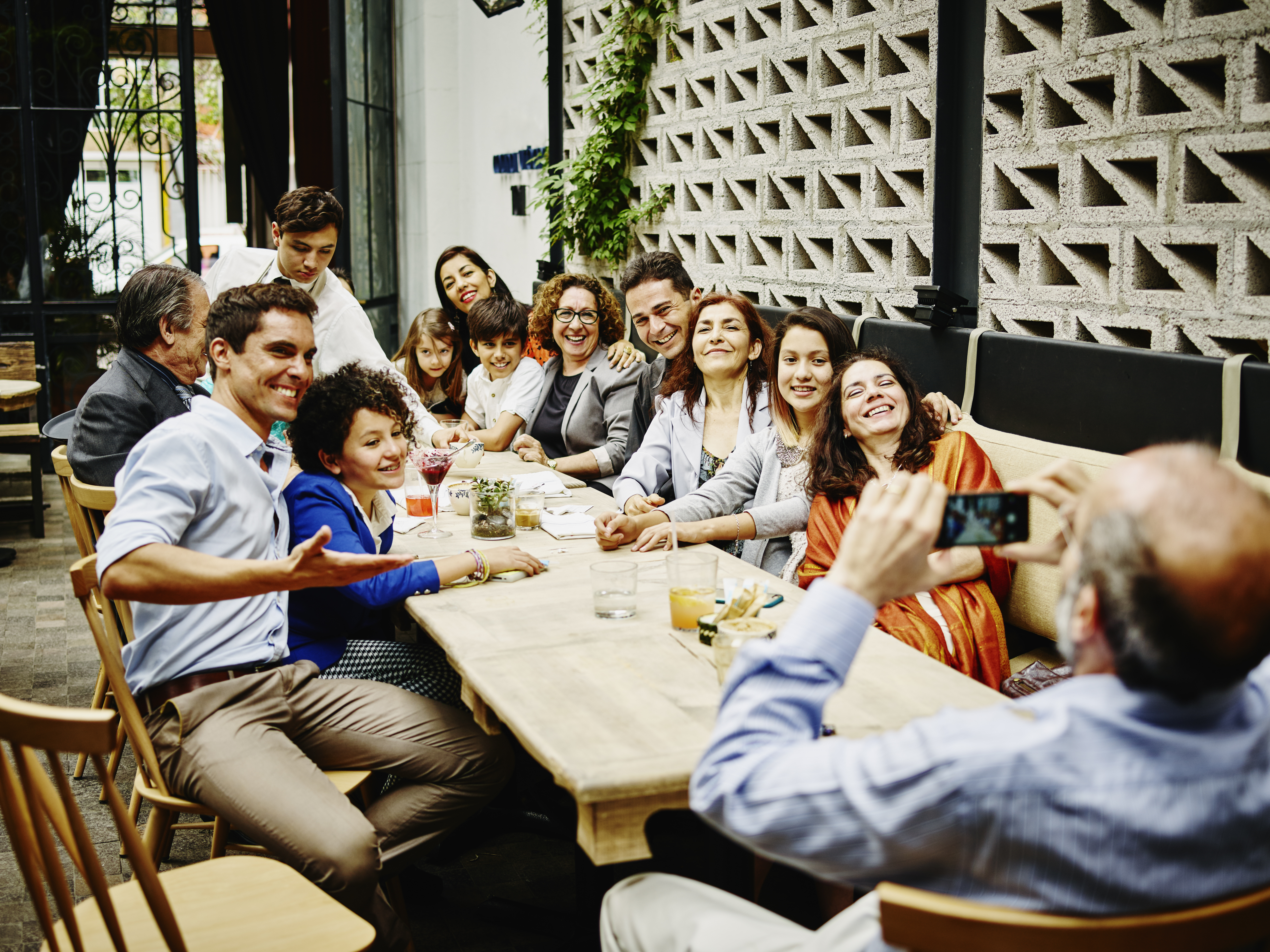 Homme prenant un portrait de famille avec son smartphone lors d'un dîner dans un restaurant | Source : Getty Images