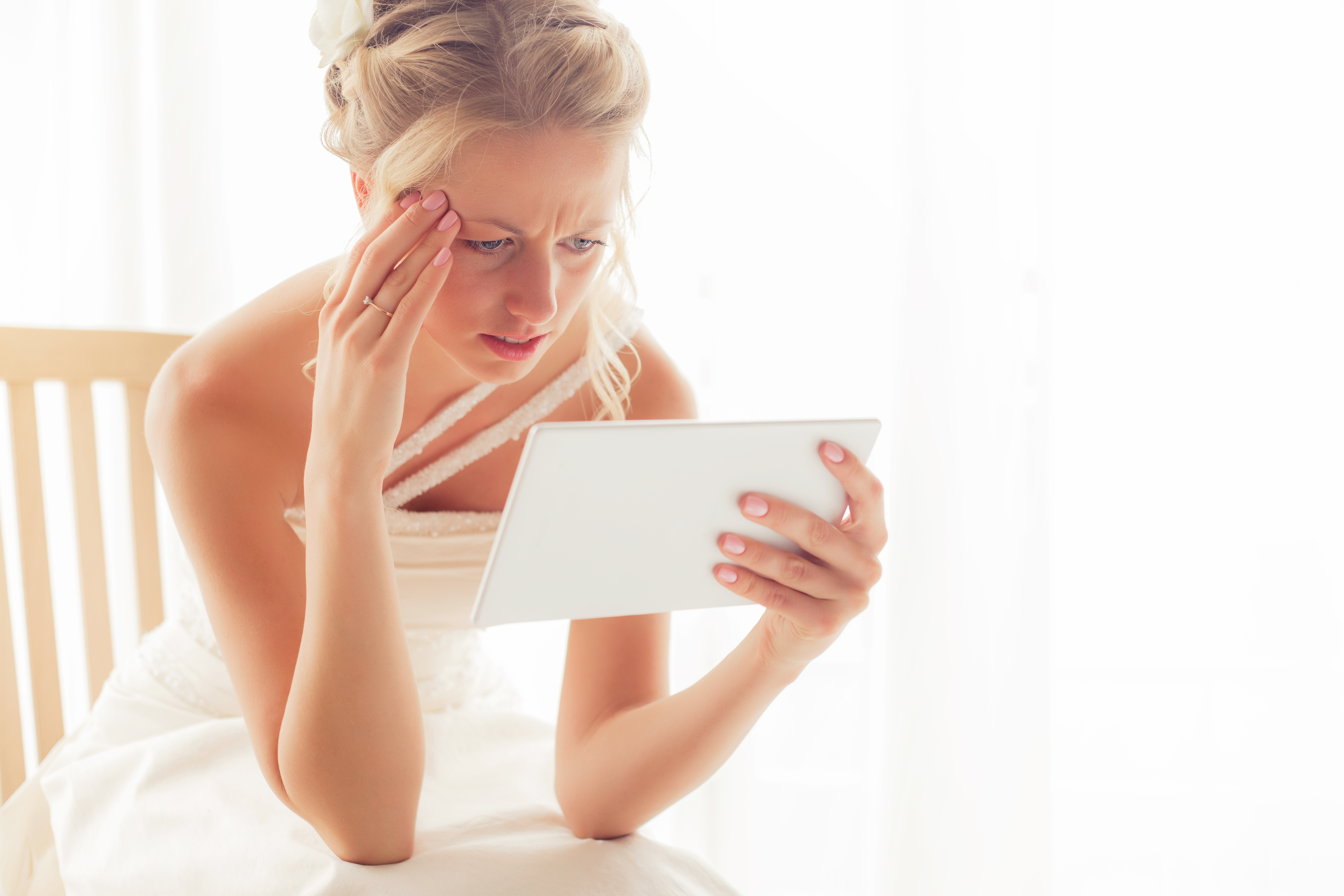 Une mariée inquiète qui regarde une tablette | Source : Shutterstock