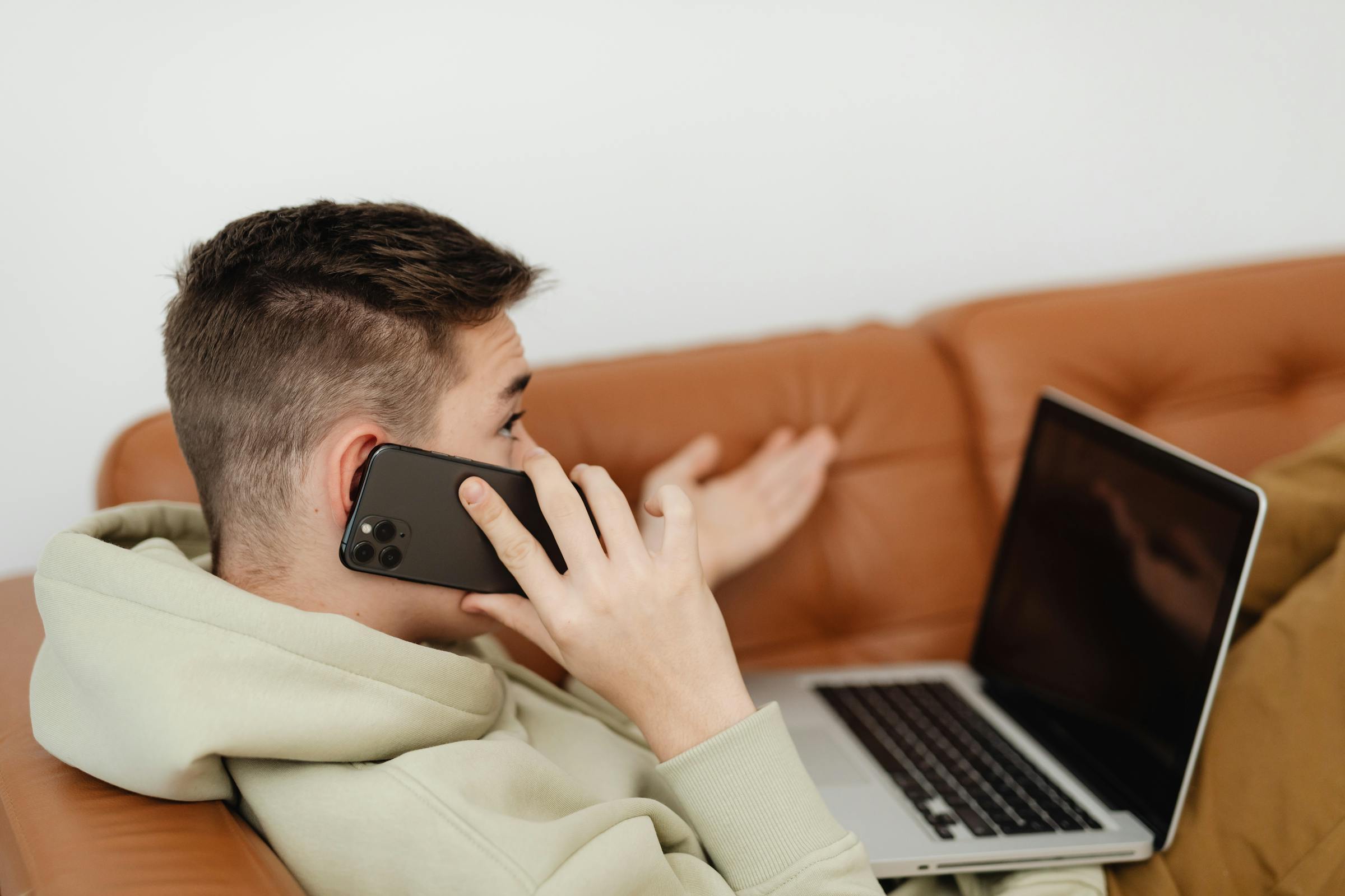 Un adolescent sur un canapé en train de parler au téléphone | Source : Pexels