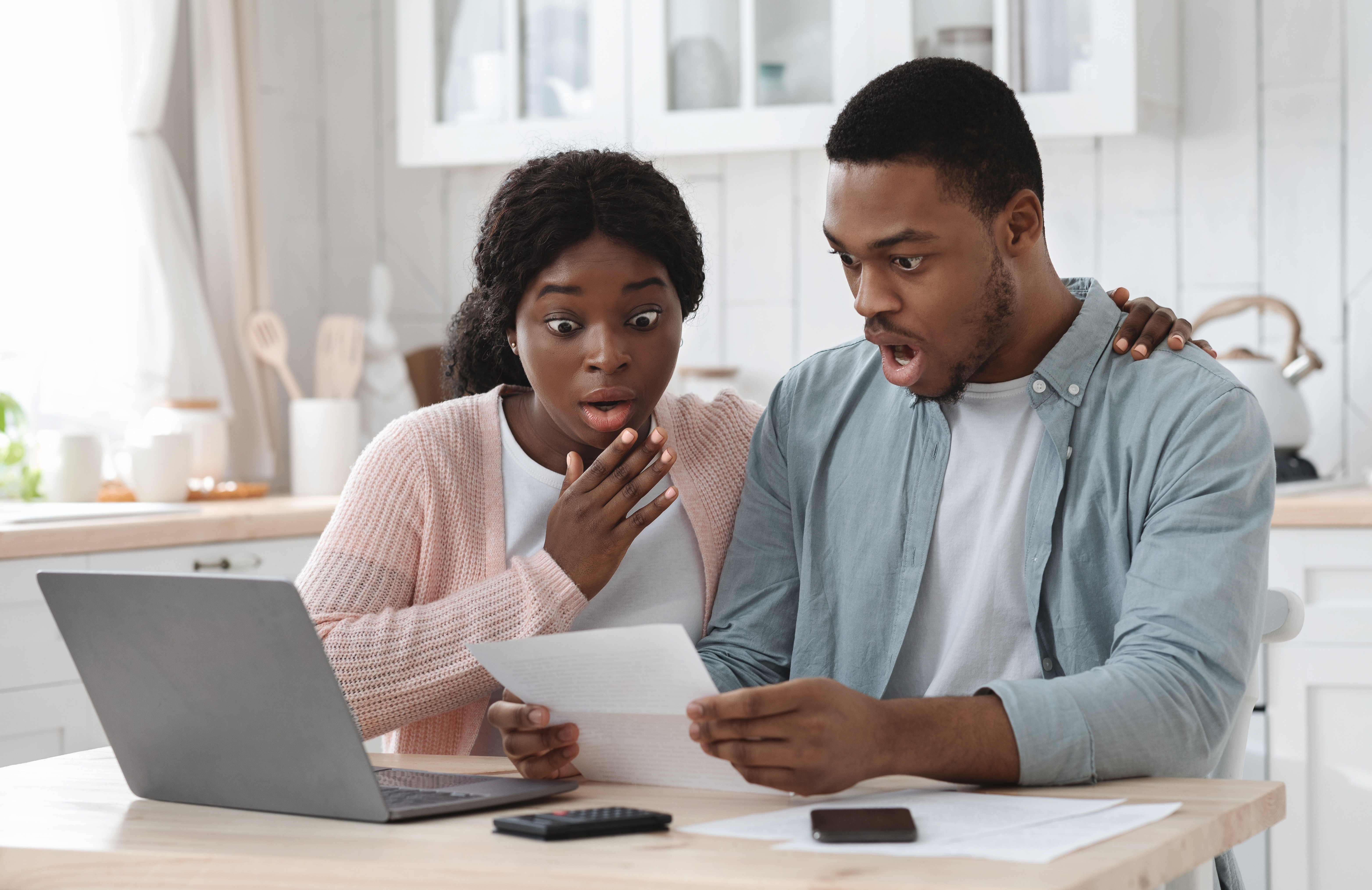 Couple noir choqué dans la cuisine ayant des problèmes financiers, faisant des calculs de budget familial | Source : Getty Images
