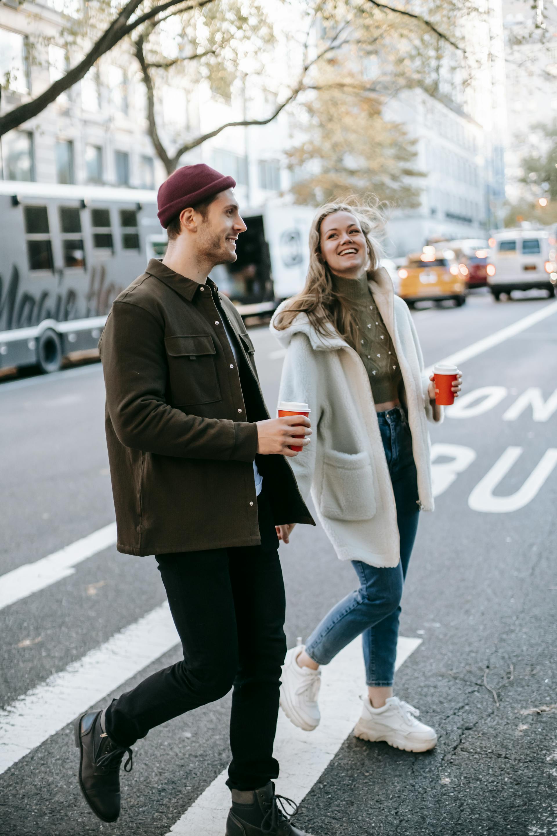 Un couple marchant dans la rue avec des tasses de café | Source : Pexels