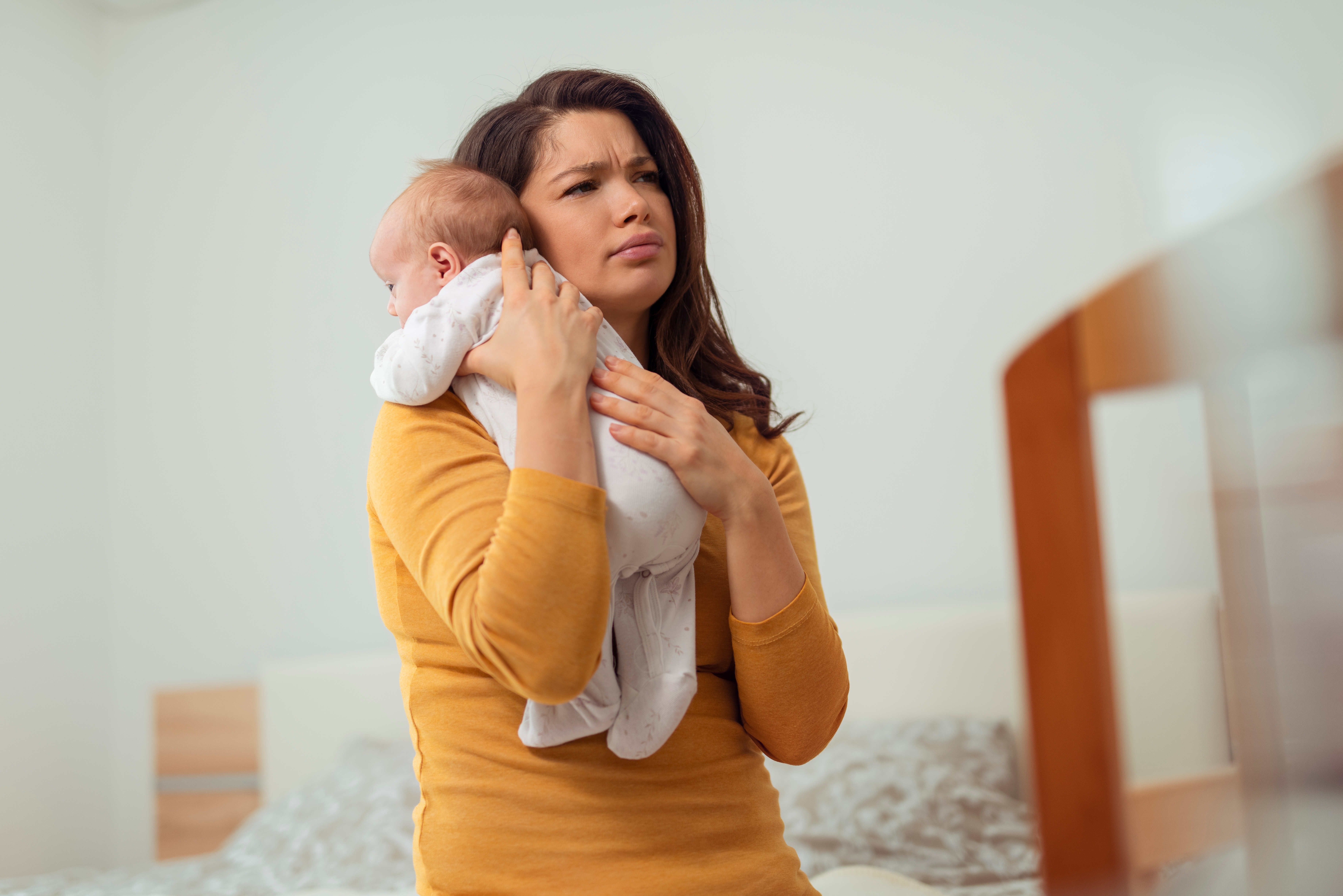 Une femme à l'air fatigué alors qu'elle tient un bébé | Source : Shutterstock