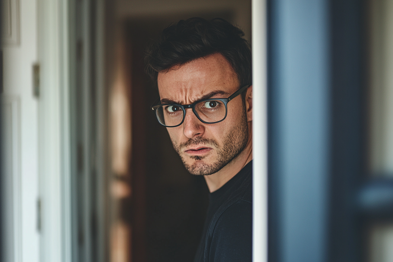 Un homme en colère visible à travers une porte entrouverte | Source : Midjourney