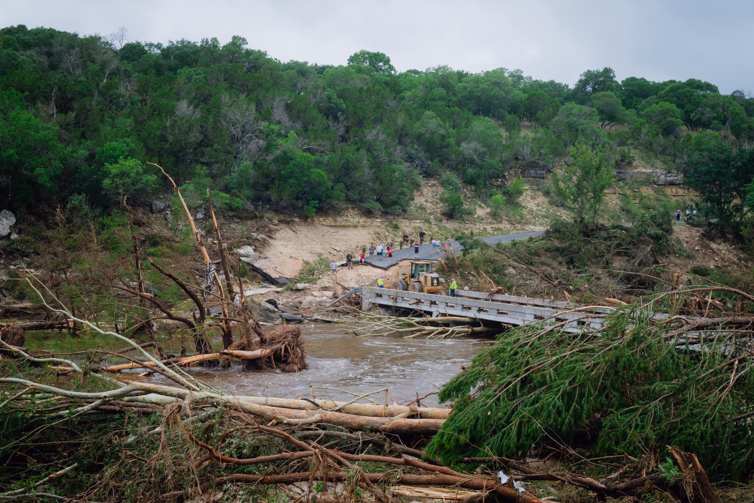 Des équipes de construction qui travaillent à dégager les débris pour permettre aux résidents de traverser un pont au-dessus de la rivière Guadalupe à Ingram, au Texas, le 5 juillet 2025. | Source : Getty Images