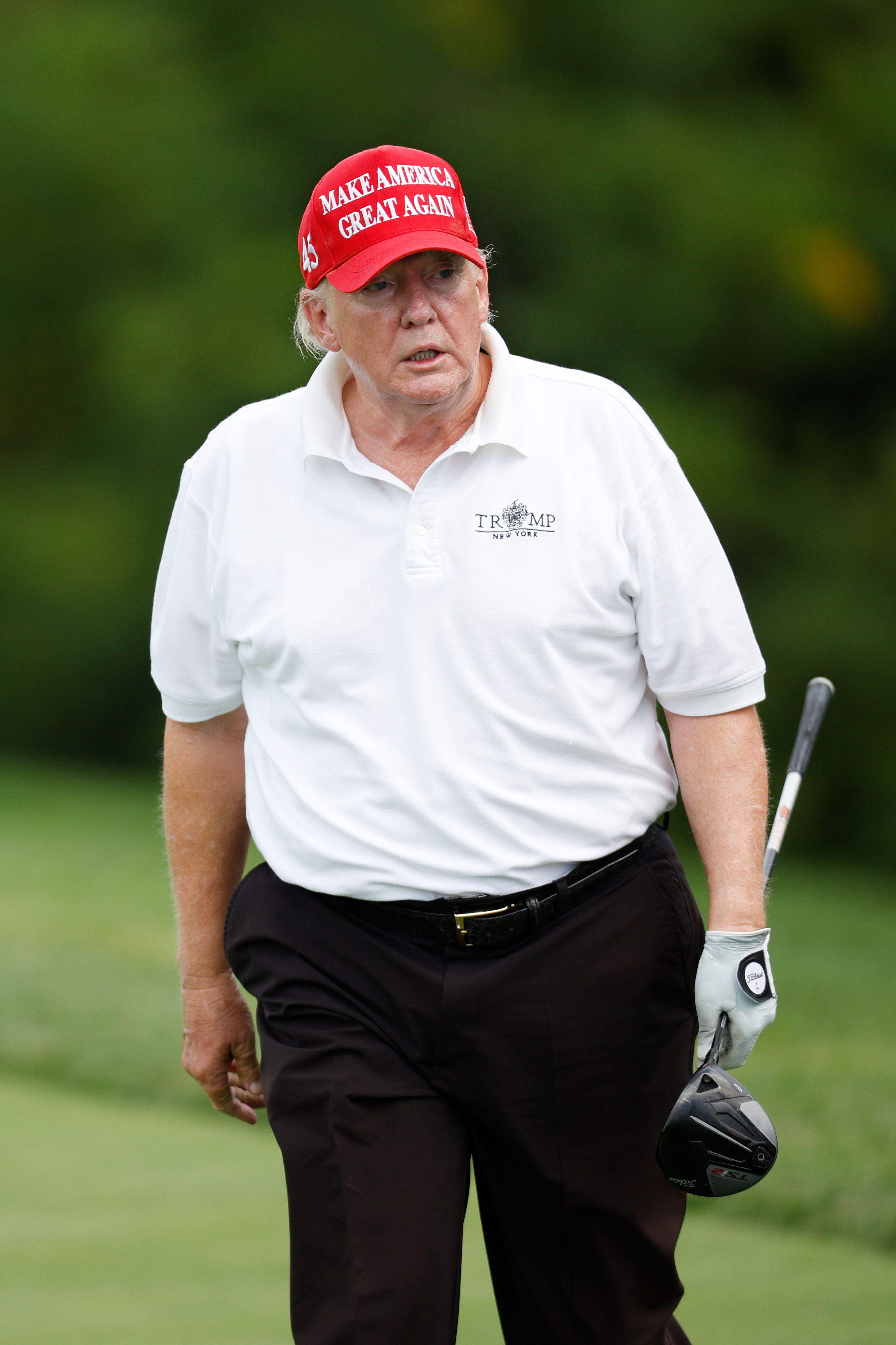 En juillet 2022, Donald Trump a été photographié au LIV Golf Invitational à Bedminster, vêtu d'un polo blanc et d'une casquette rouge. Son visage présente des teintes de peau différentes, sans signes évidents de maquillage.