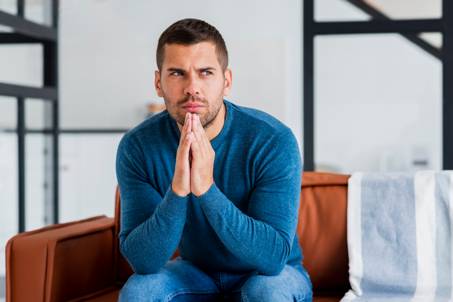 Un homme anxieux assis sur le canapé | Source : Freepik