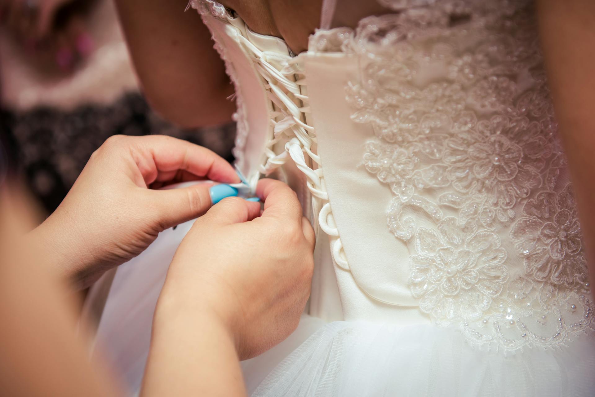 Gros plan d'une femme fixant une robe de mariée | Source : Pexels