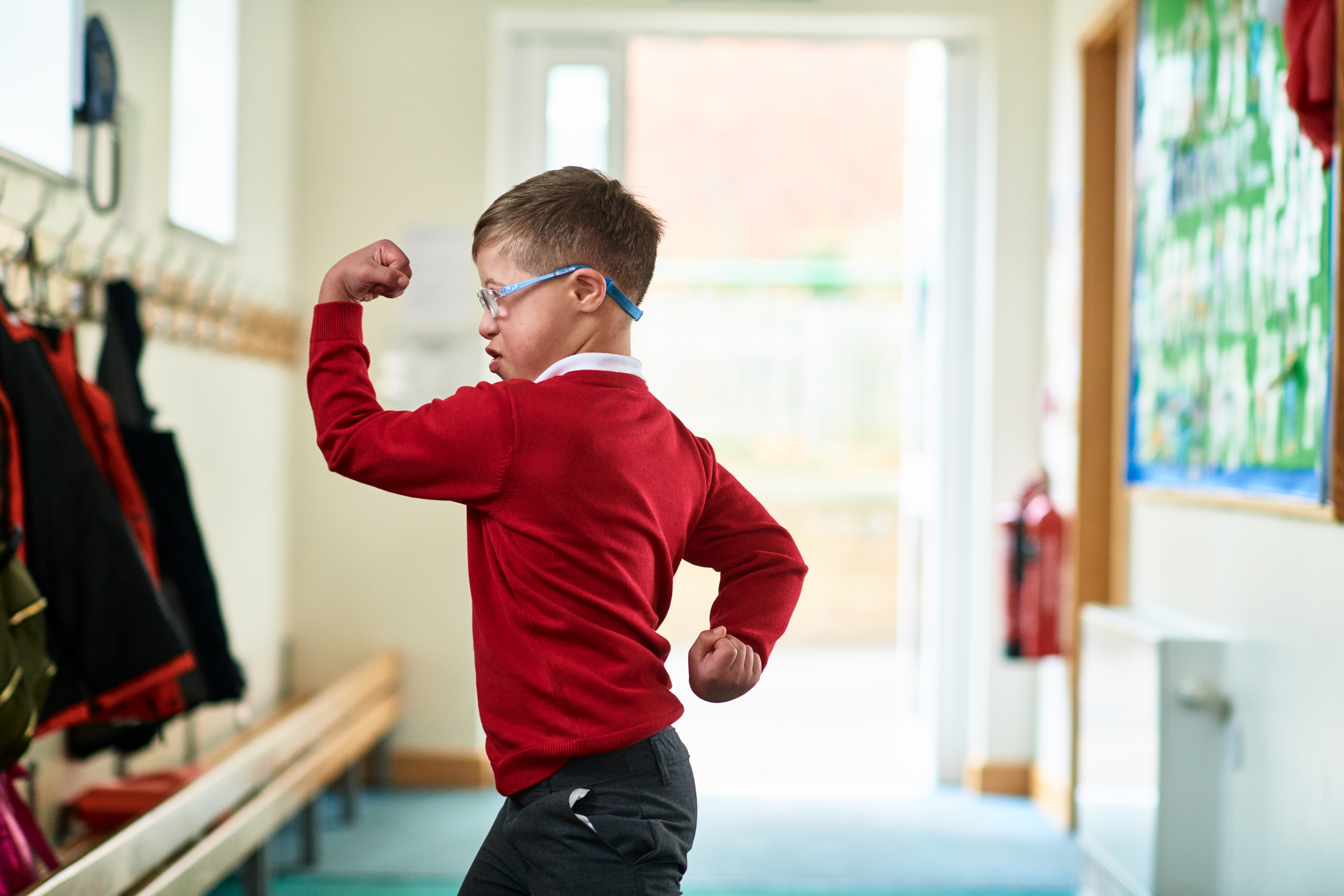 Un garçon atteint du syndrome de Down montre ses muscles dans le couloir de l'école | Source : Getty Images