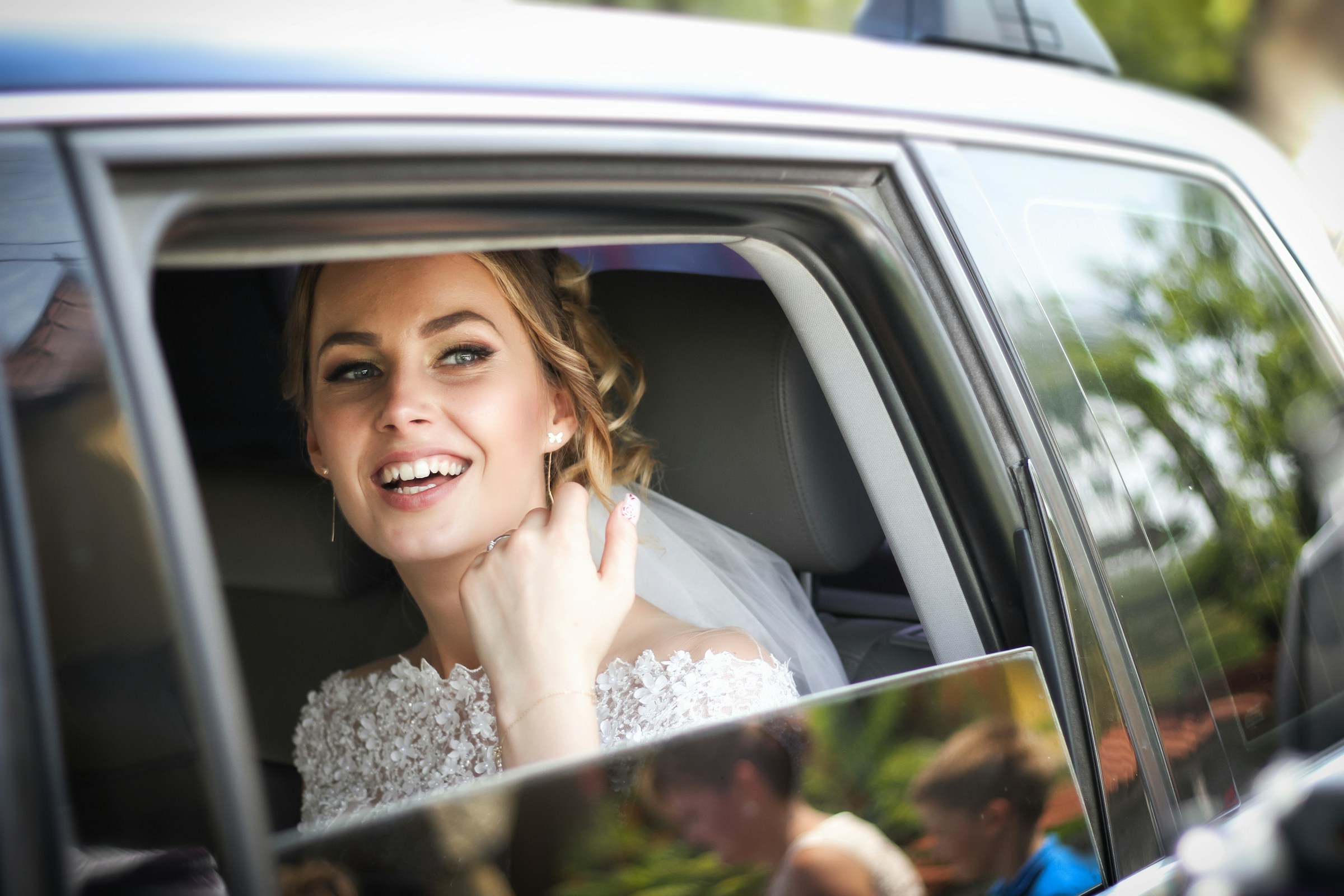 Une mariée dans une voiture qui regarde dehors et sourit | Source : Unsplash