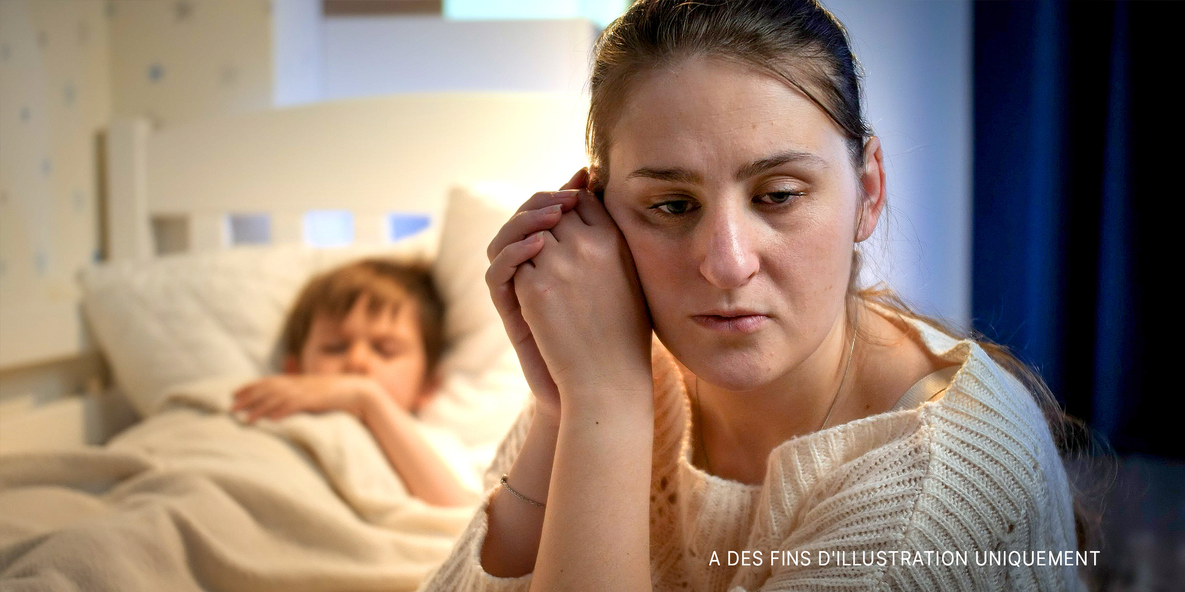 Une femme bouleversée assise à côté d'un enfant qui dort dans son lit | Source : Shutterstock