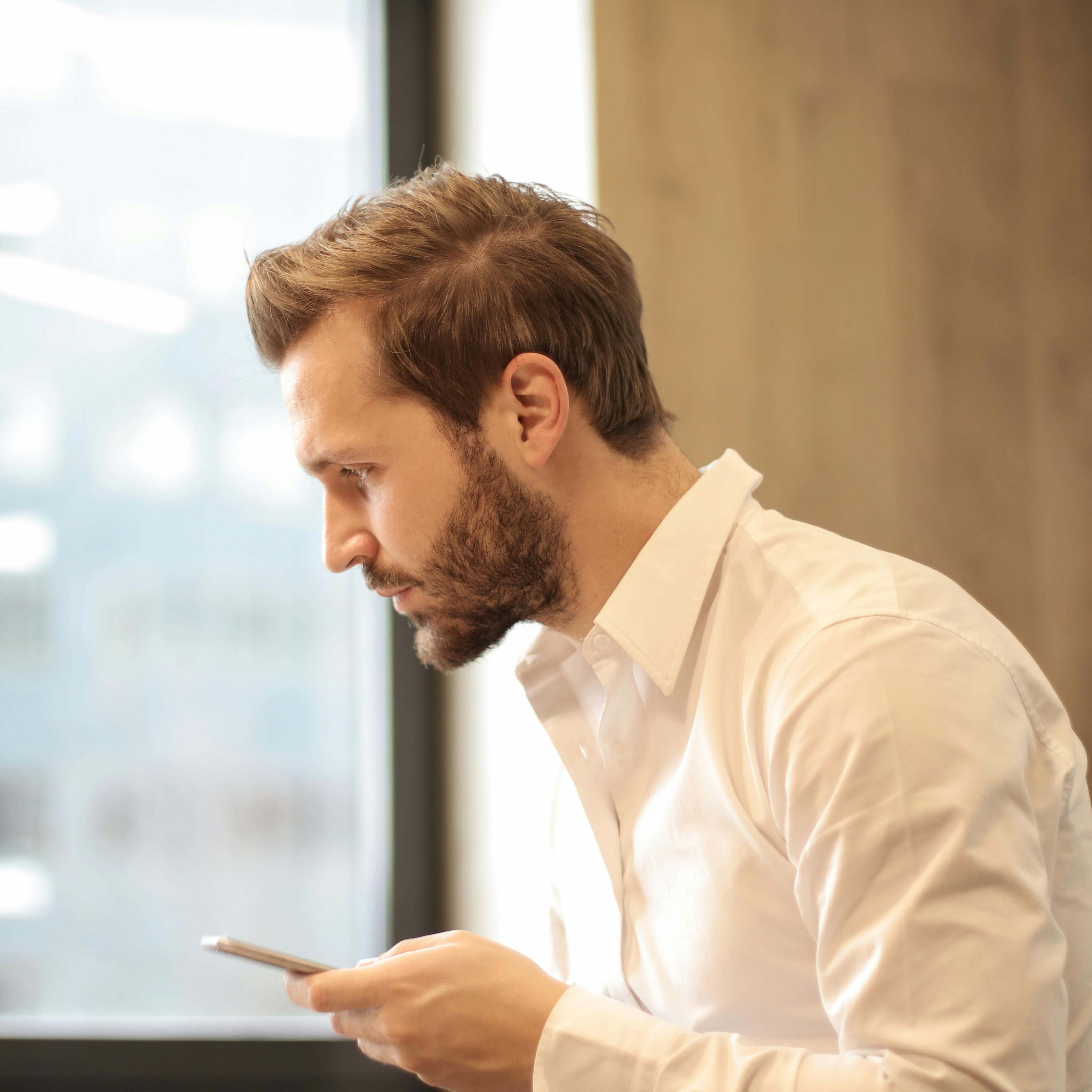 Un homme tenant un téléphone, l'air contemplatif | Source : Pexels