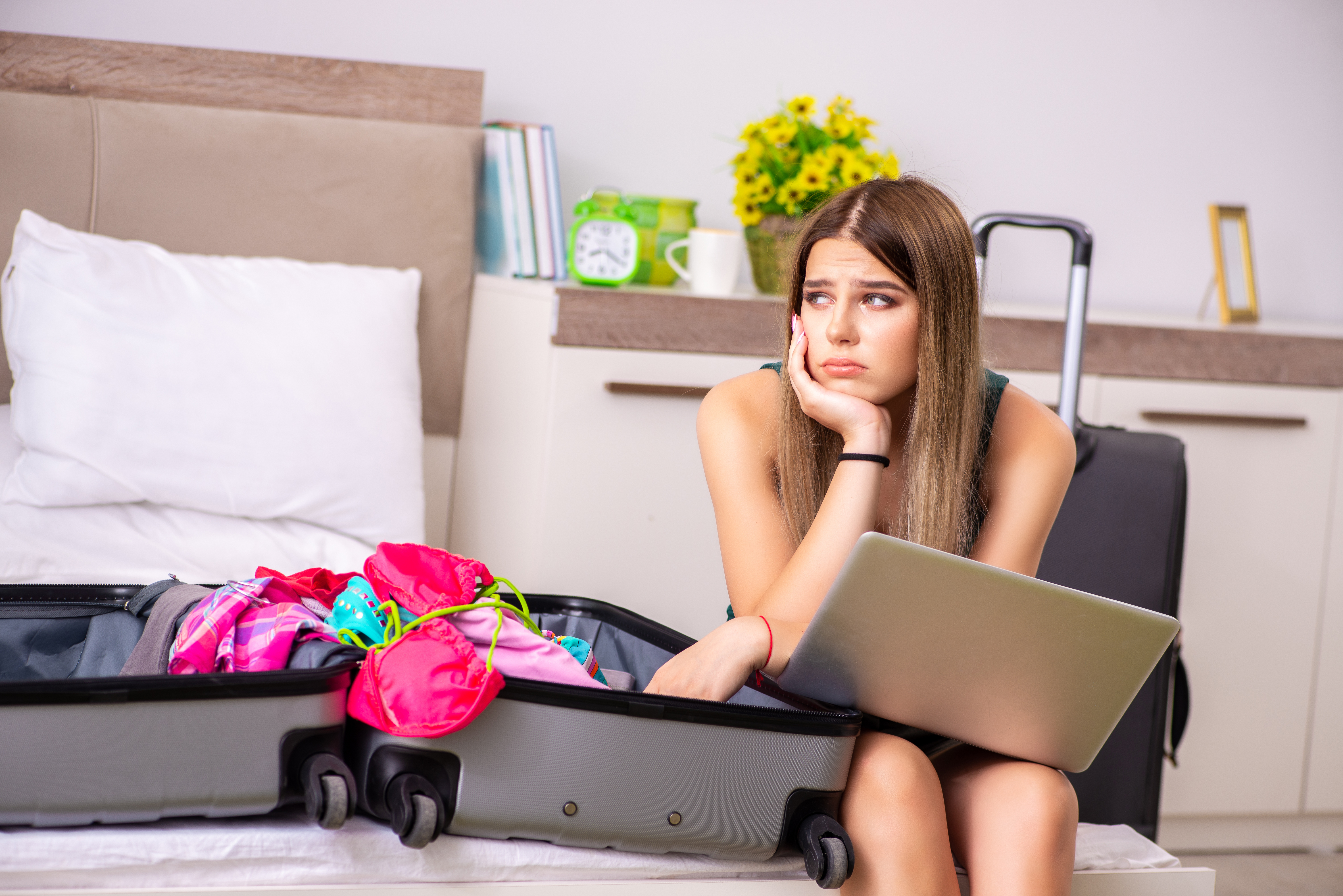 Jeune fille contrariée assise à côté d'une valise emballée | Source : Shutterstock