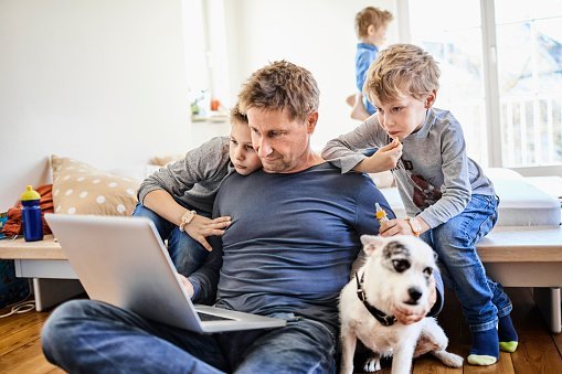 Père utilisant un ordinateur portable à la maison avec des enfants.| Photo: Getty Images.