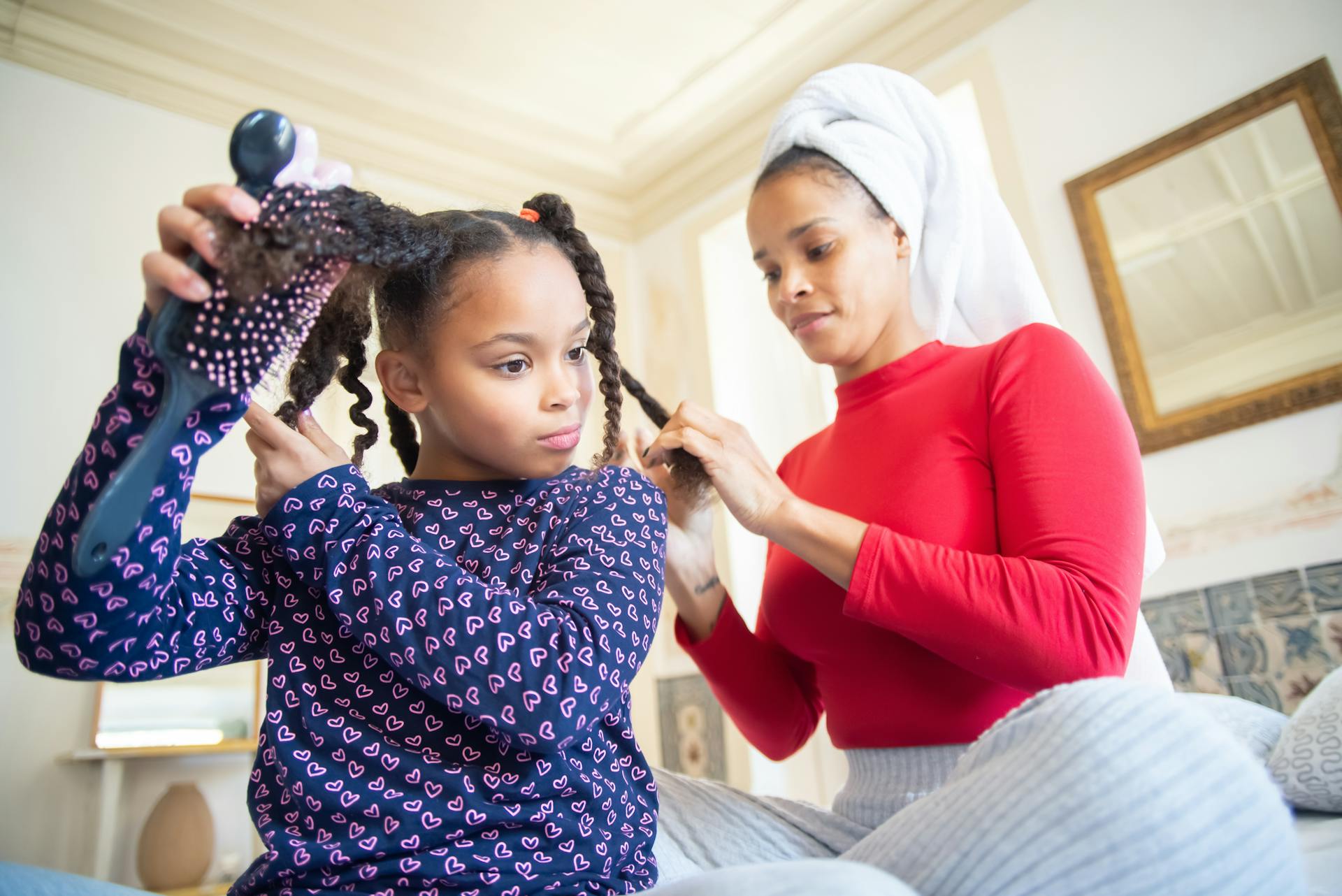 Une mère tressant les cheveux de sa fille | Source : Pexels