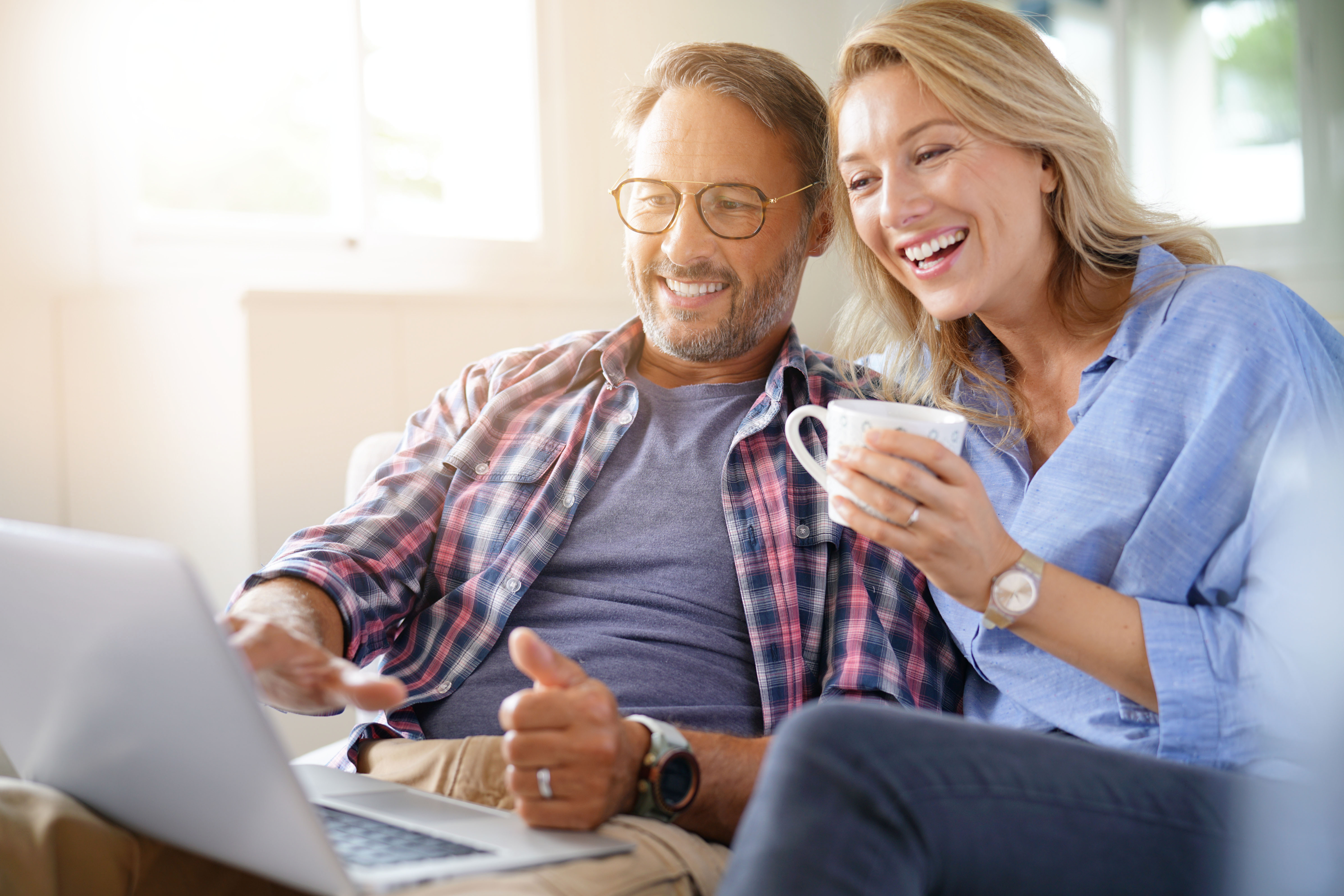 Un homme et une femme souriant en regardant un ordinateur portable | Source : Shutterstock