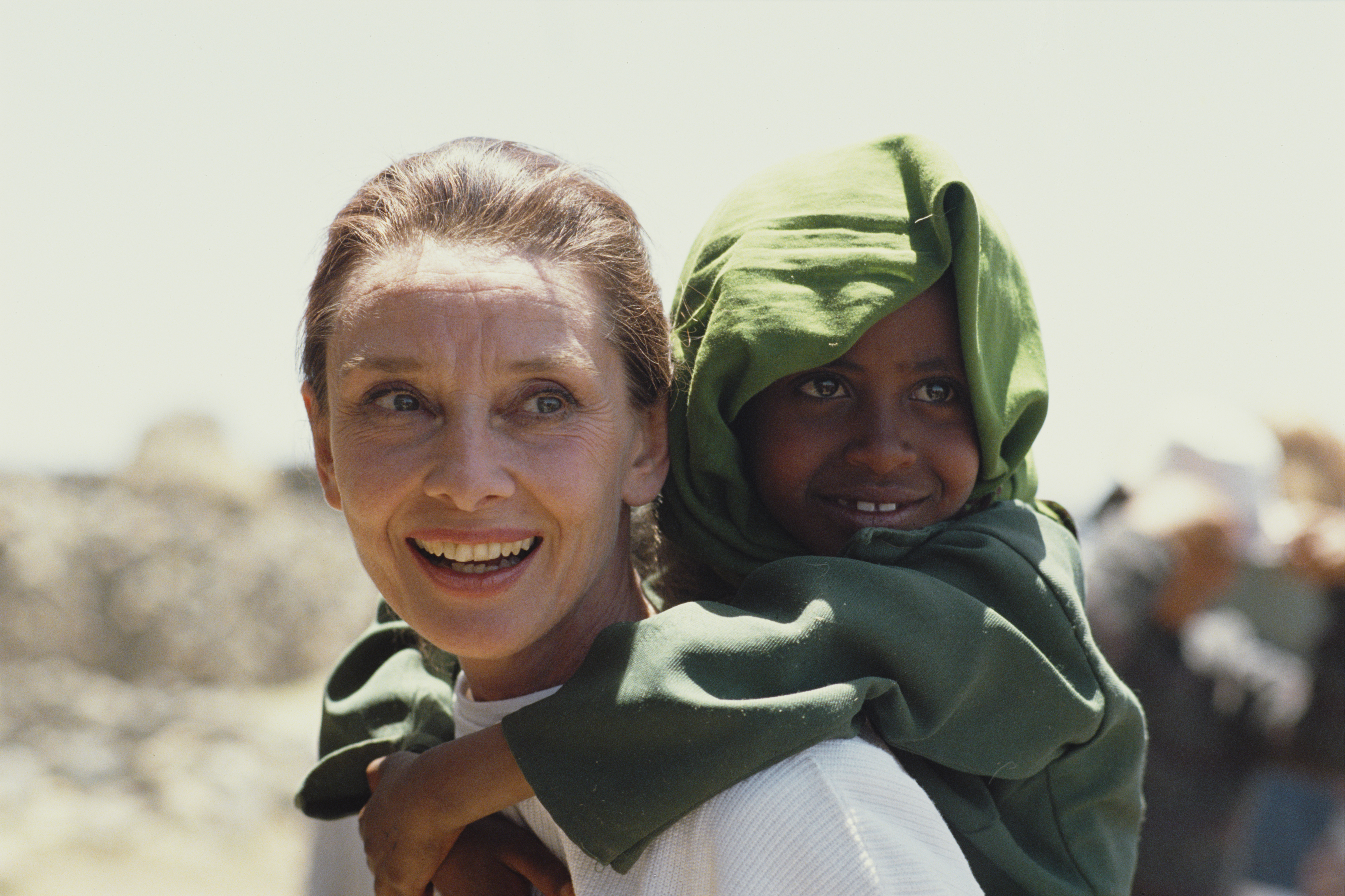 Audrey Hepburn portant une fillette éthiopienne sur son dos lors de sa première mission sur le terrain pour l'UNICEF en Éthiopie, en mars 1988. | Source : Getty Images