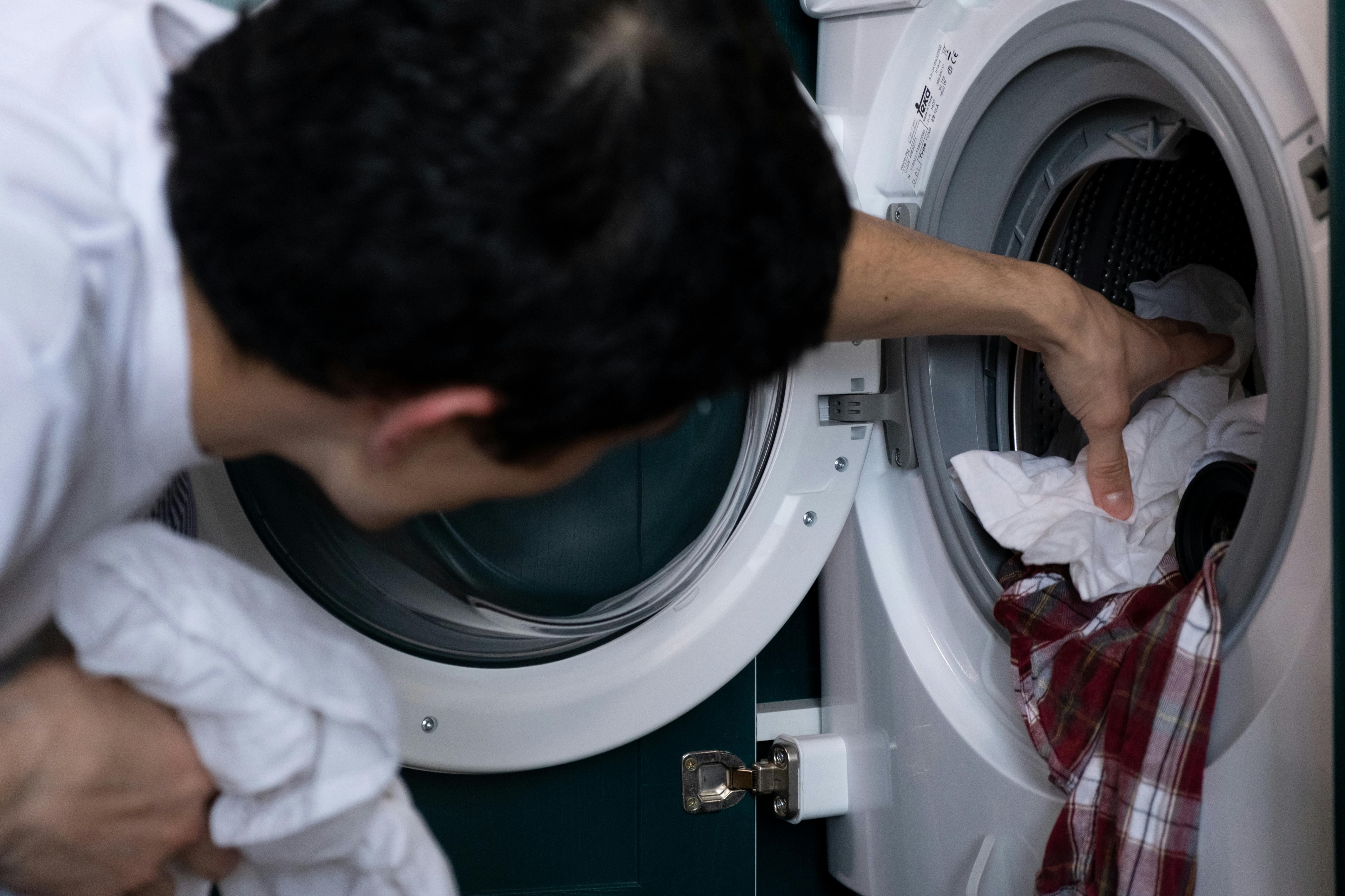 Un homme mettant des vêtements dans une machine à laver | Source : Pexels