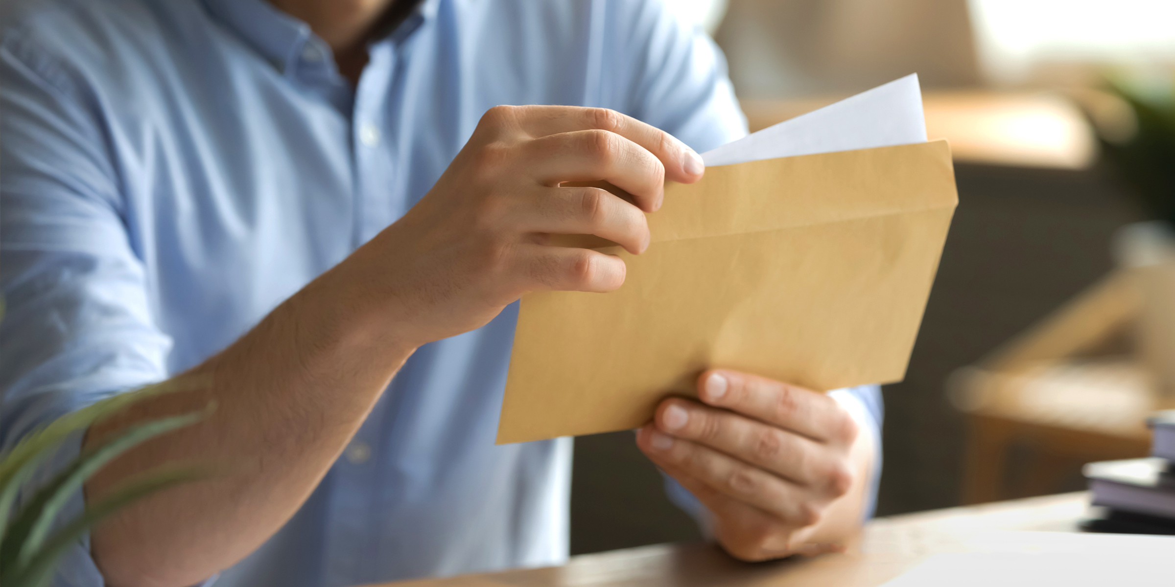 Un homme qui ouvre une enveloppe et en retire une lettre | Source : Shutterstock