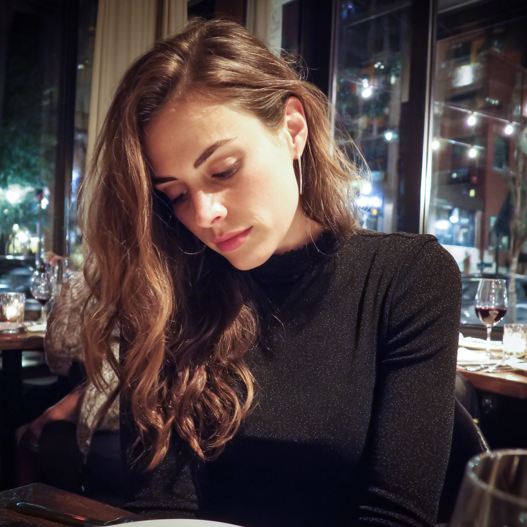 Une femme qui regarde ses genoux dans un restaurant | Source : Midjourney