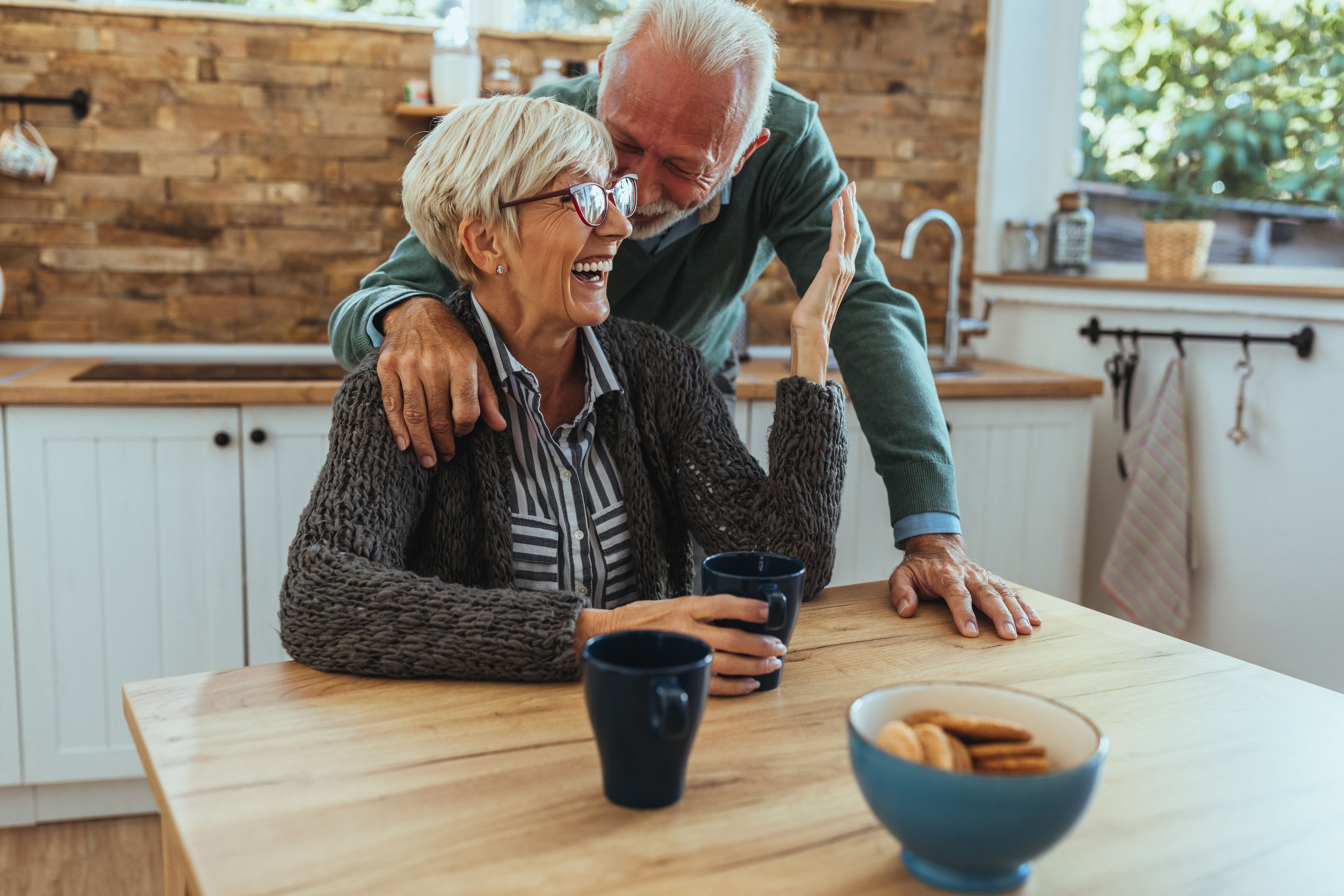 Un couple de personnes âgées souriant dans la cuisine. | Source : Shutterstock