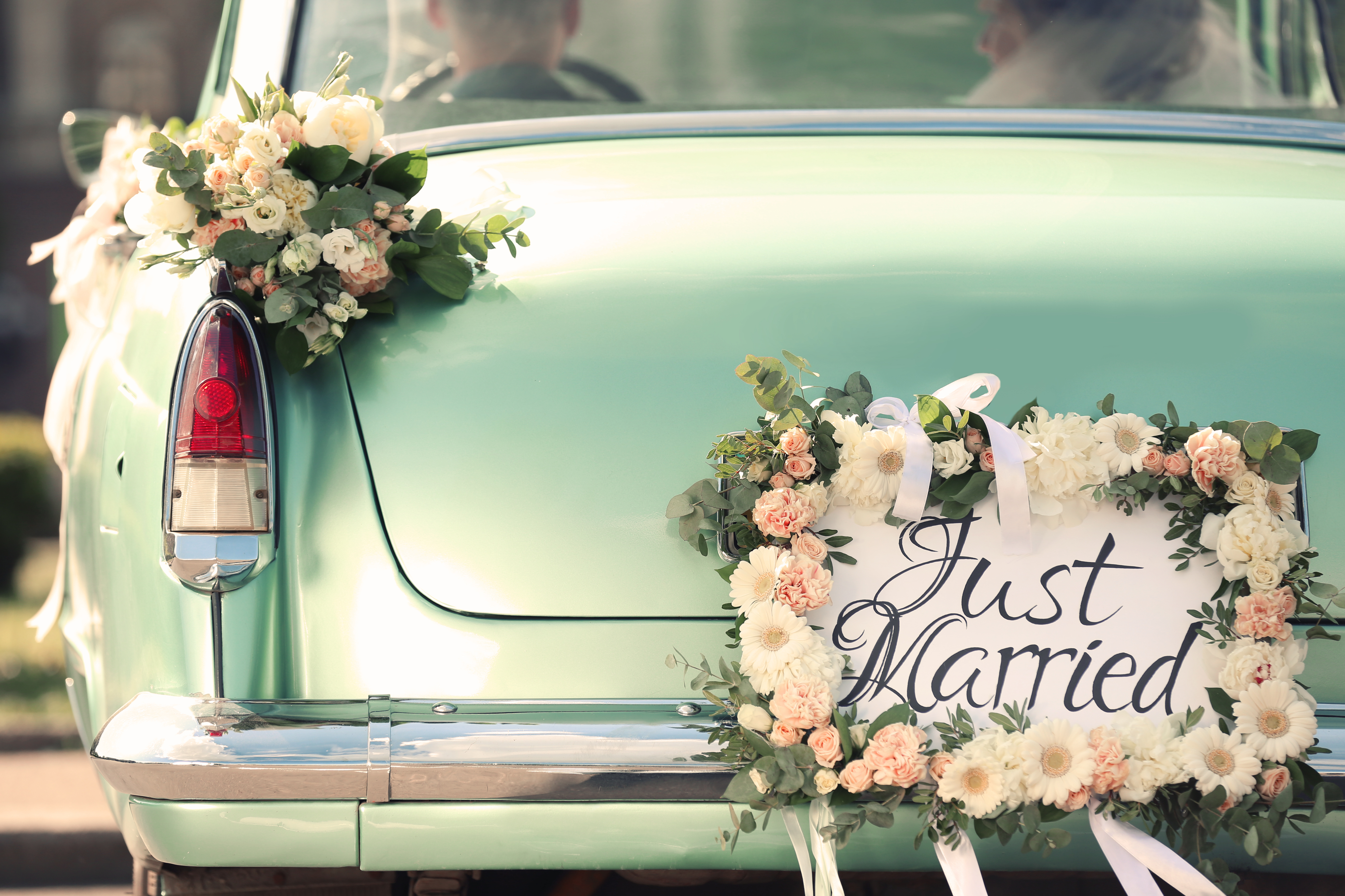 Une voiture avec une plaque "Jeunes mariés" et un décor floral. | Source : Shutterstock