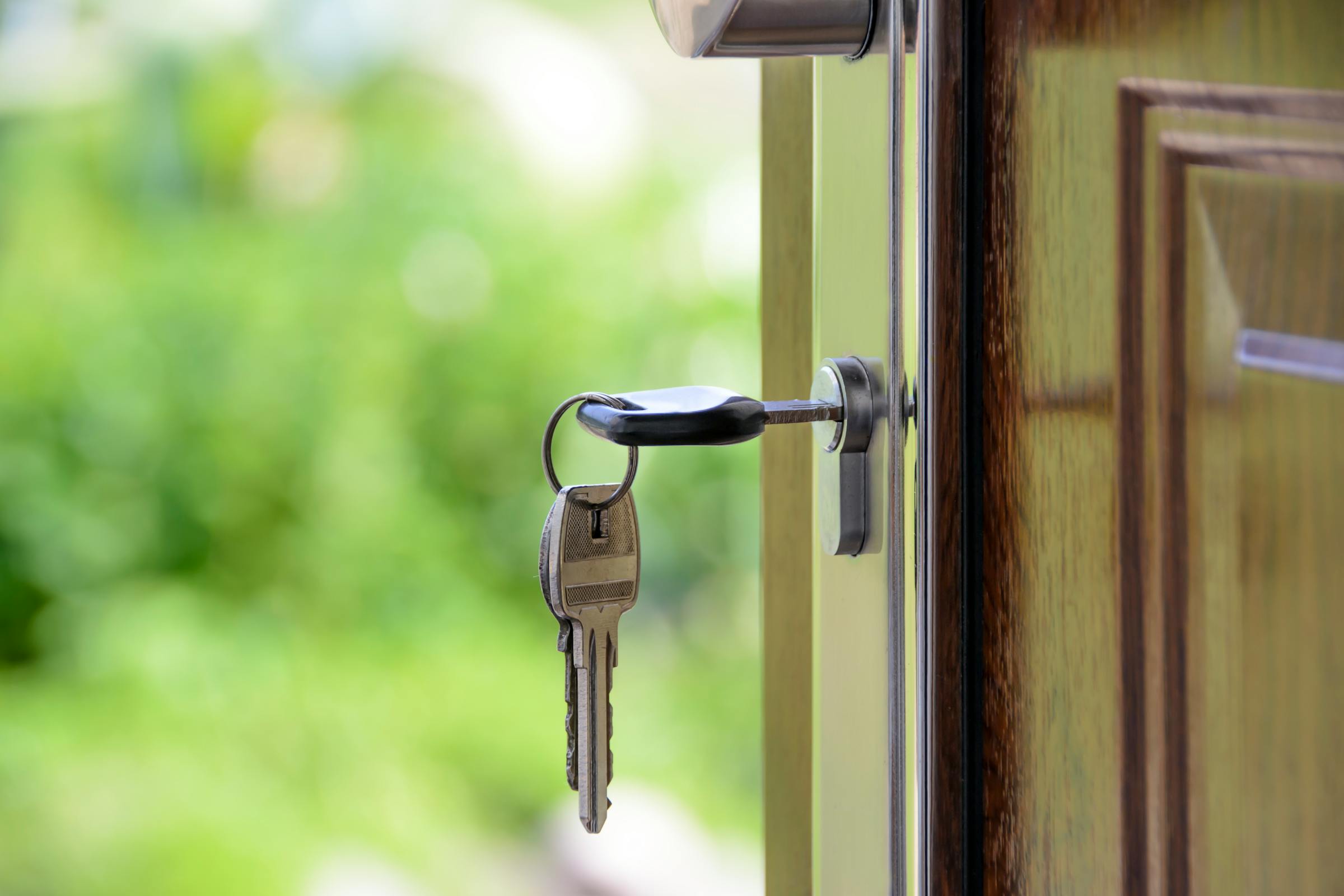 Une clé dans la porte d'entrée d'une maison avec l'ouverture de la porte | Source : Pexels