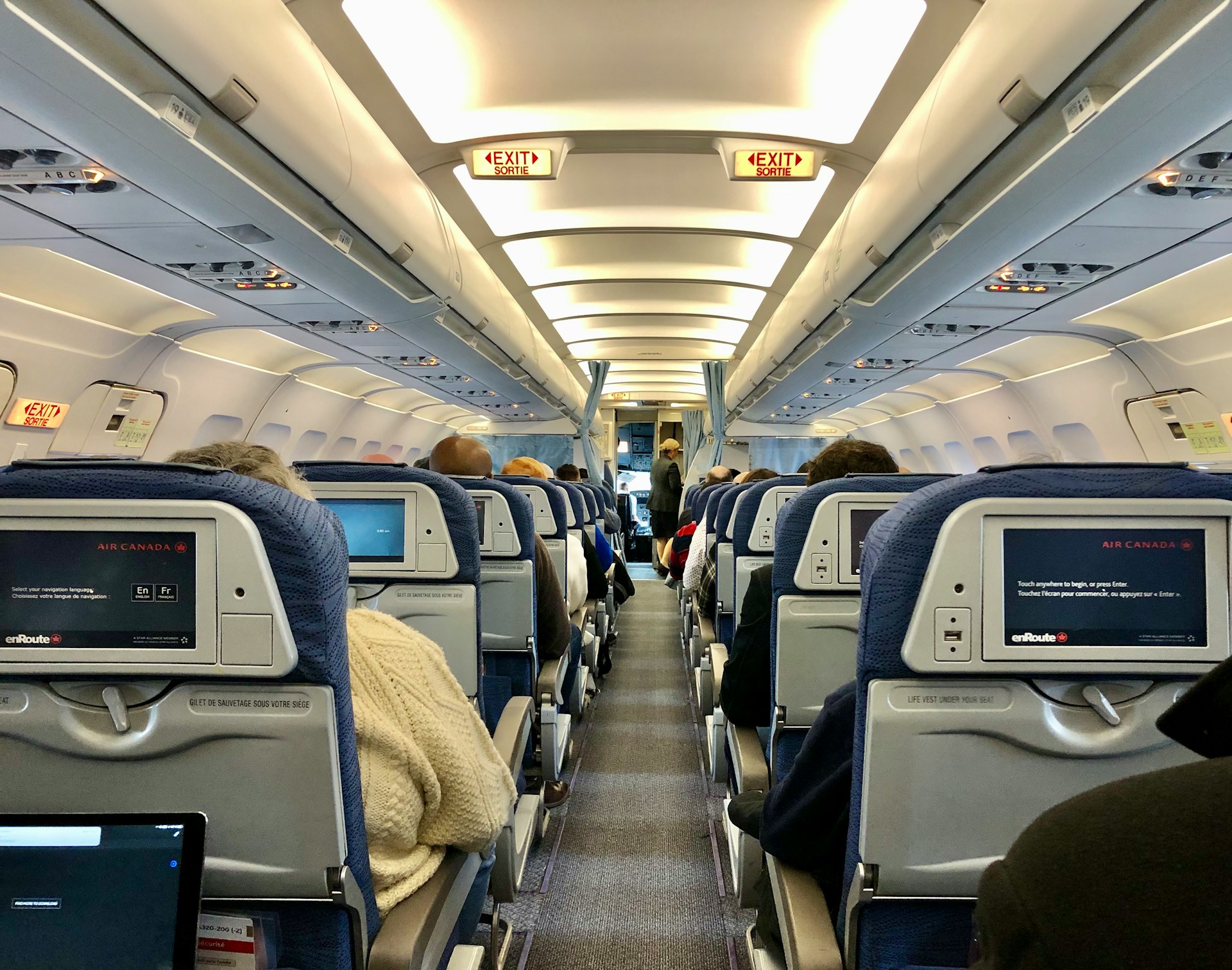 Passagers d'un vol assis dans l'allée économique | Source : Unsplash