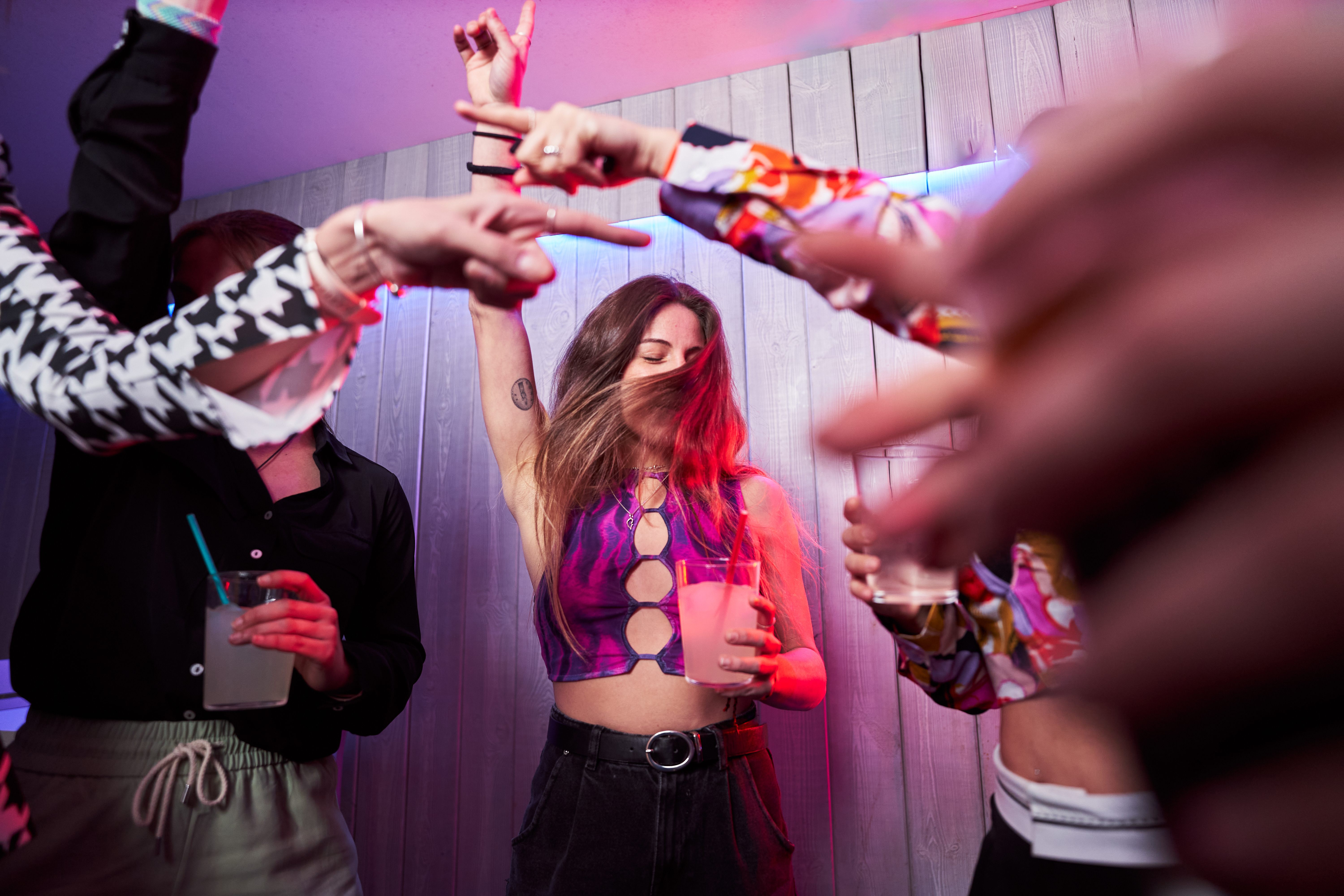 Des amis heureux dansent ensemble dans une boîte de nuit | Source : Getty Images