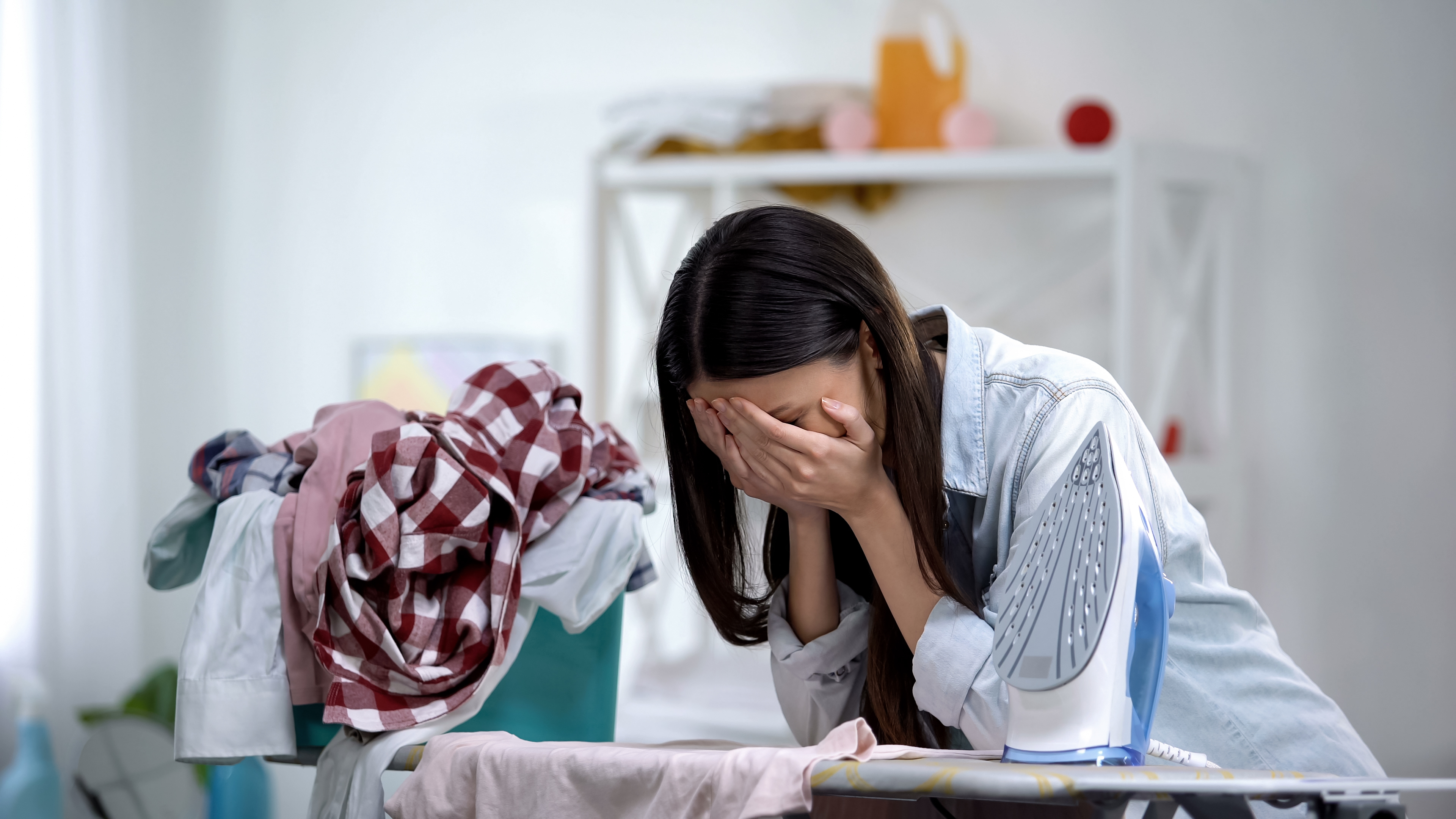 Une femme stressée est photographiée en train de pleurer en s'appuyant sur la planche à repasser | Source : Shutterstock