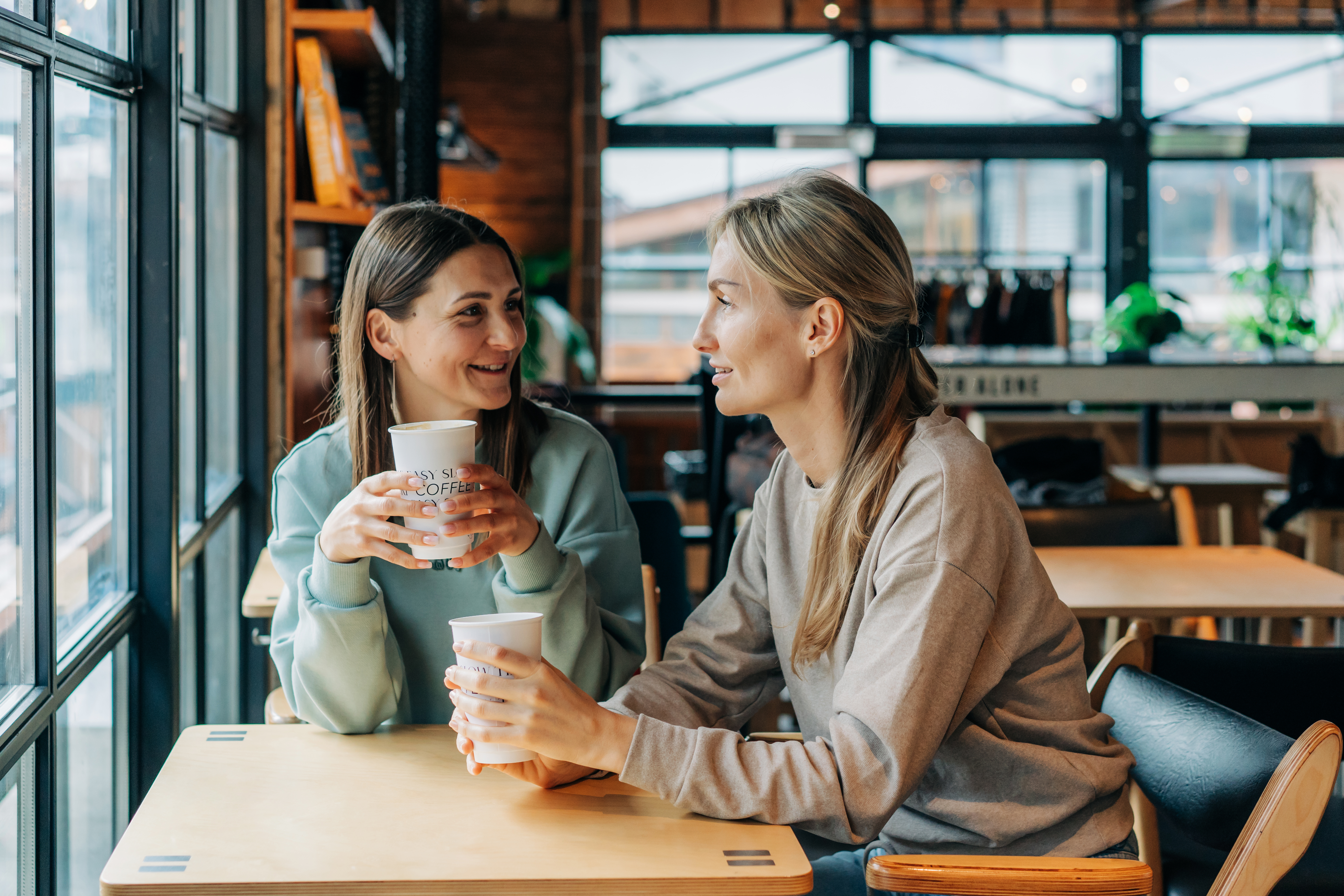 Deux femmes assises dans un café en train de parler et de boire du café | Source : Getty Images