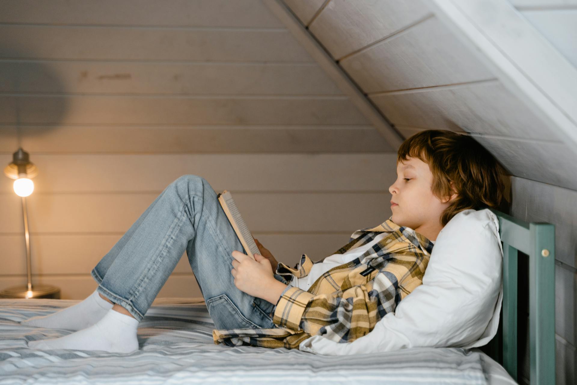 Un garçon qui lit sur son lit | Source : Pexels