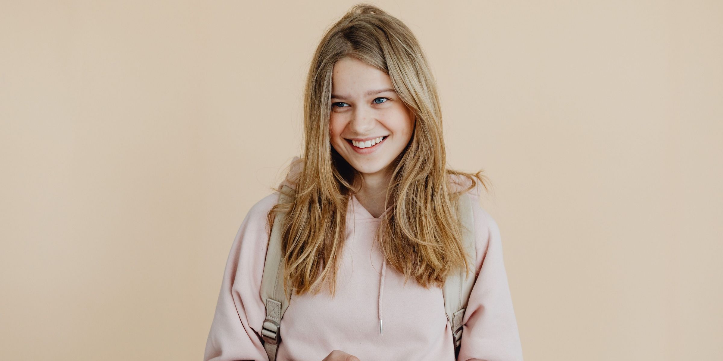 Une jeune femme souriante portant un sweat à capuche rose | Source : Pexels