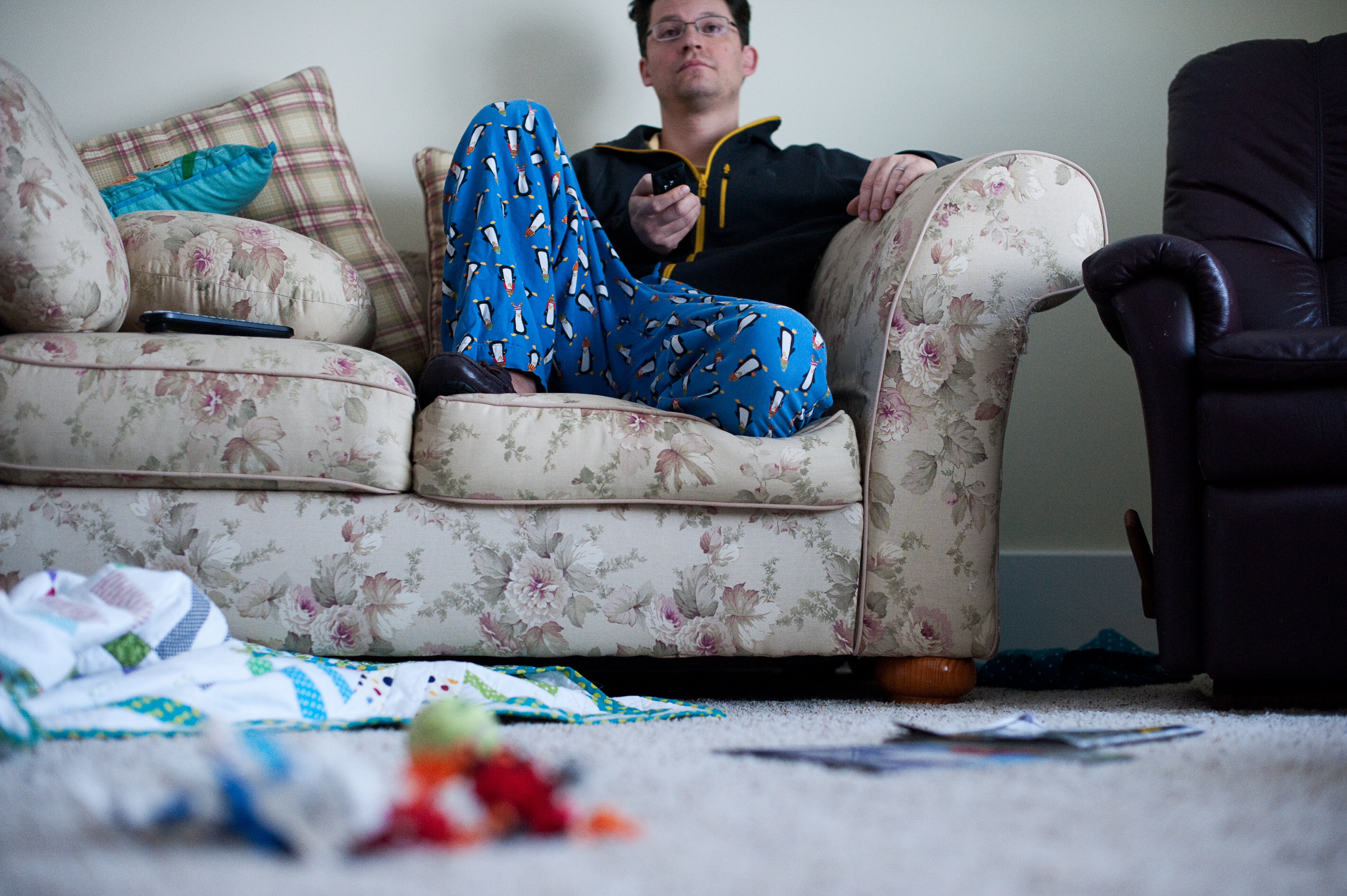 Un homme paresseux assis et regardant la télévision avec une maison en désordre | Source : Getty Images