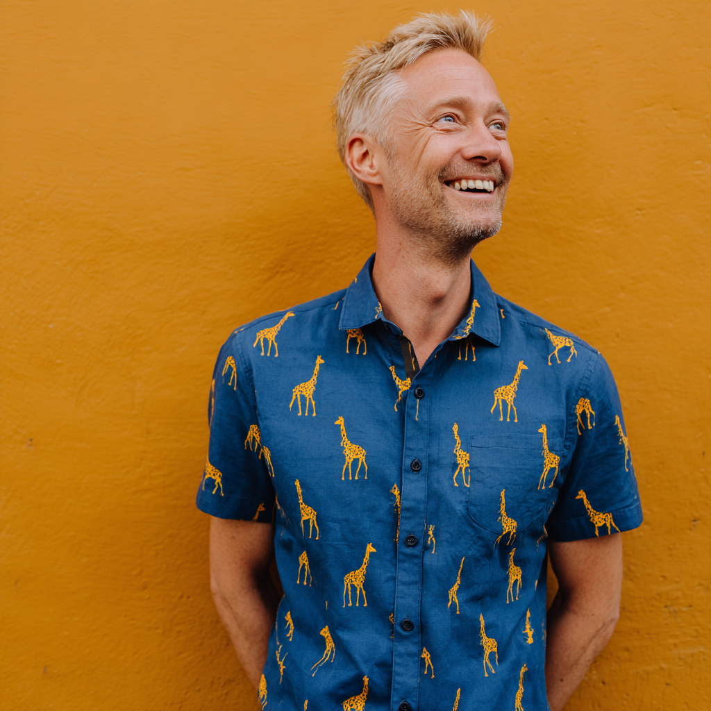 Un homme souriant portant une chemise imprimée d'une girafe | Source : Midjourney