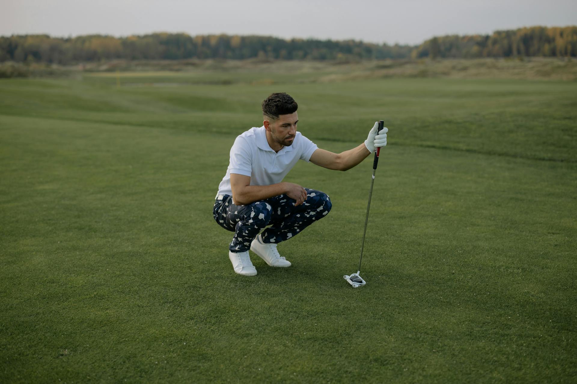 Un homme tenant un putter assis sur une pelouse | Source : Pexels
