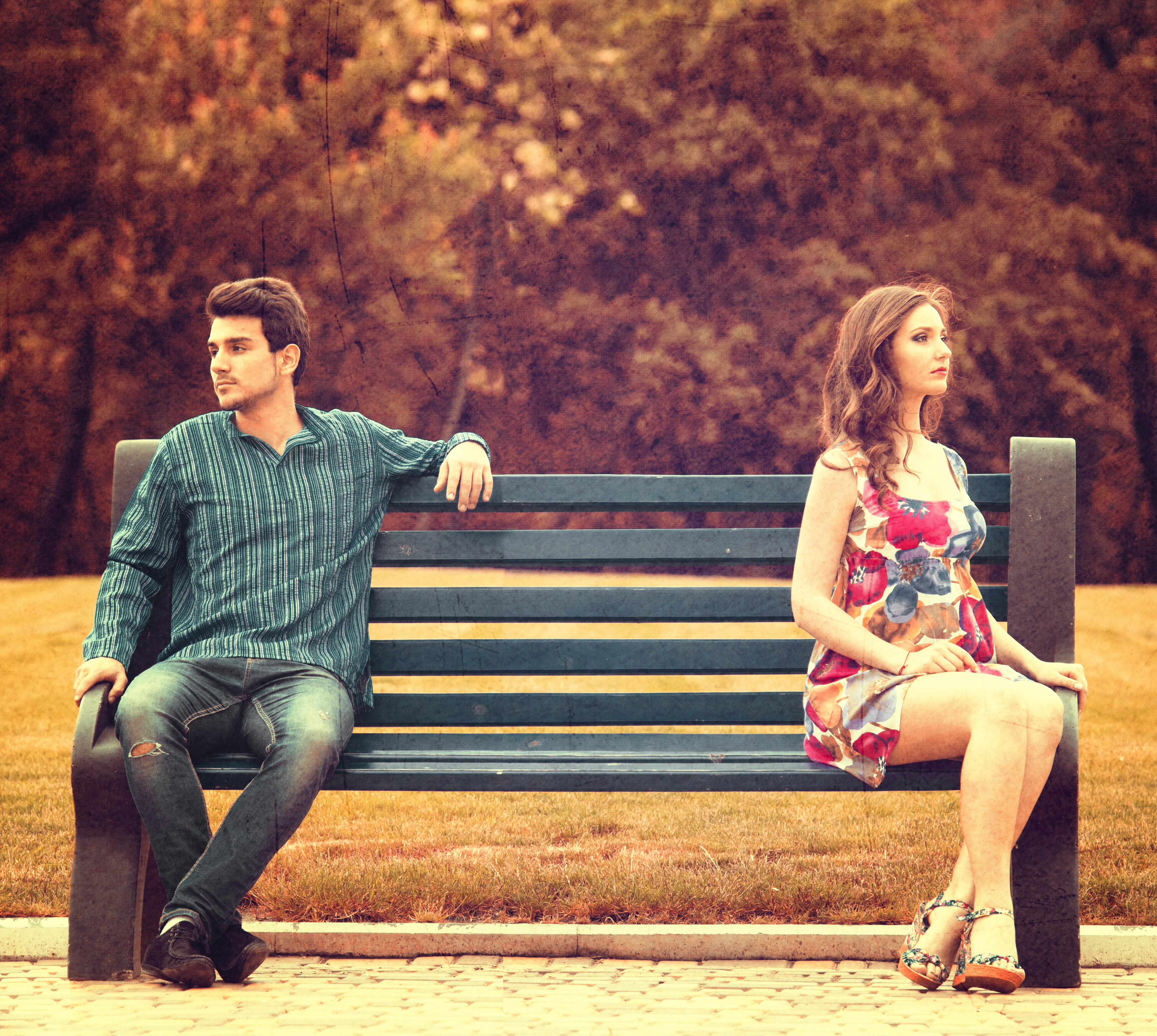 Un jeune couple assis à l'écart sur un banc public | Source : Shutterstock