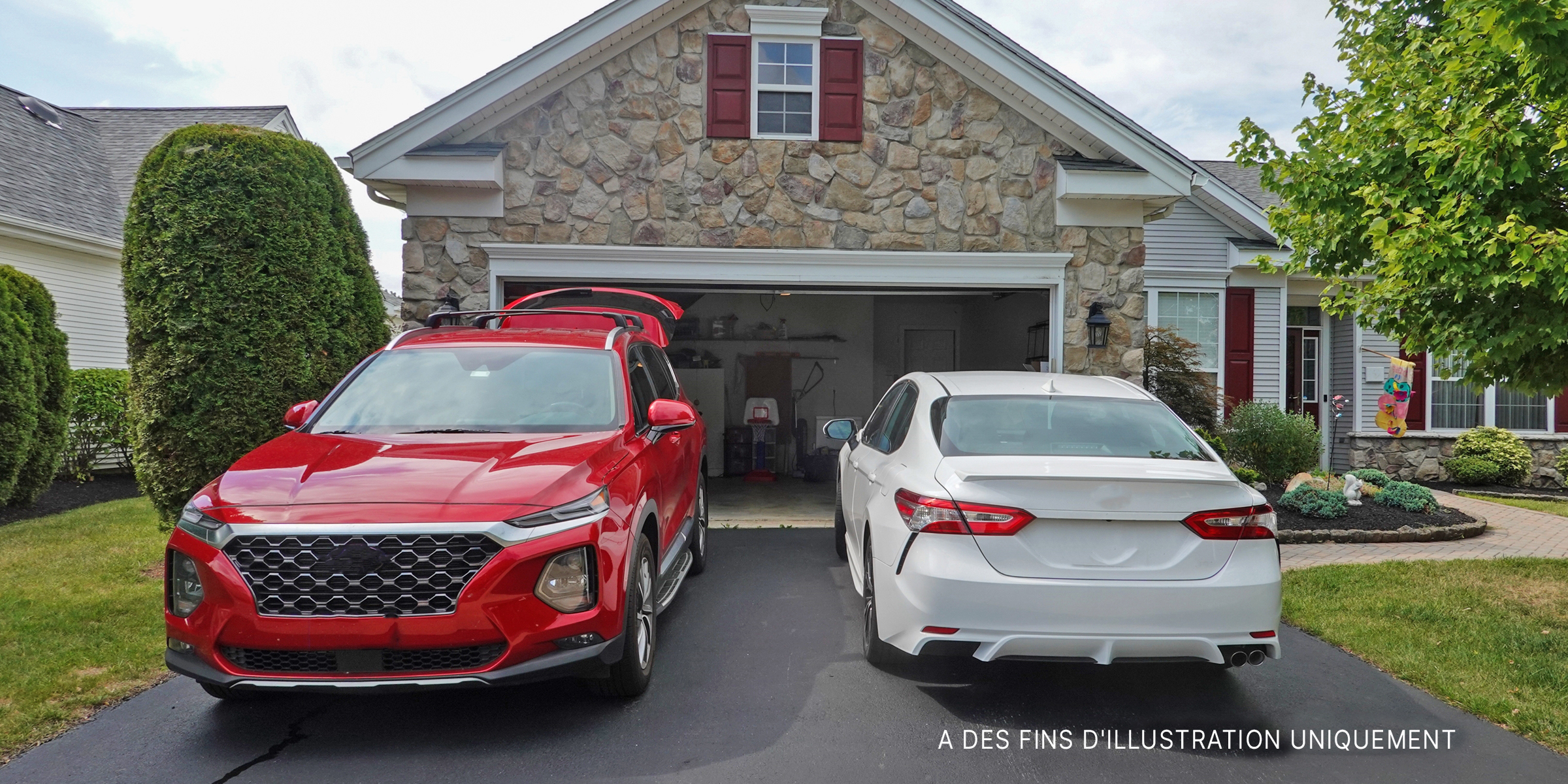 Un SUV rouge et une berline blanche garés dans une allée | Source : Shutterstock