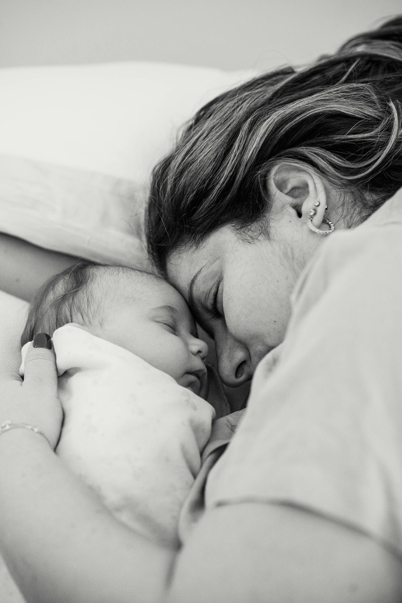Photo en niveaux de gris d'une femme allongée à côté de son bébé | Source : Pexels