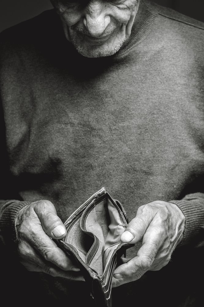 Un homme âgé tenant un portefeuille vide. | Photo: Shutterstock