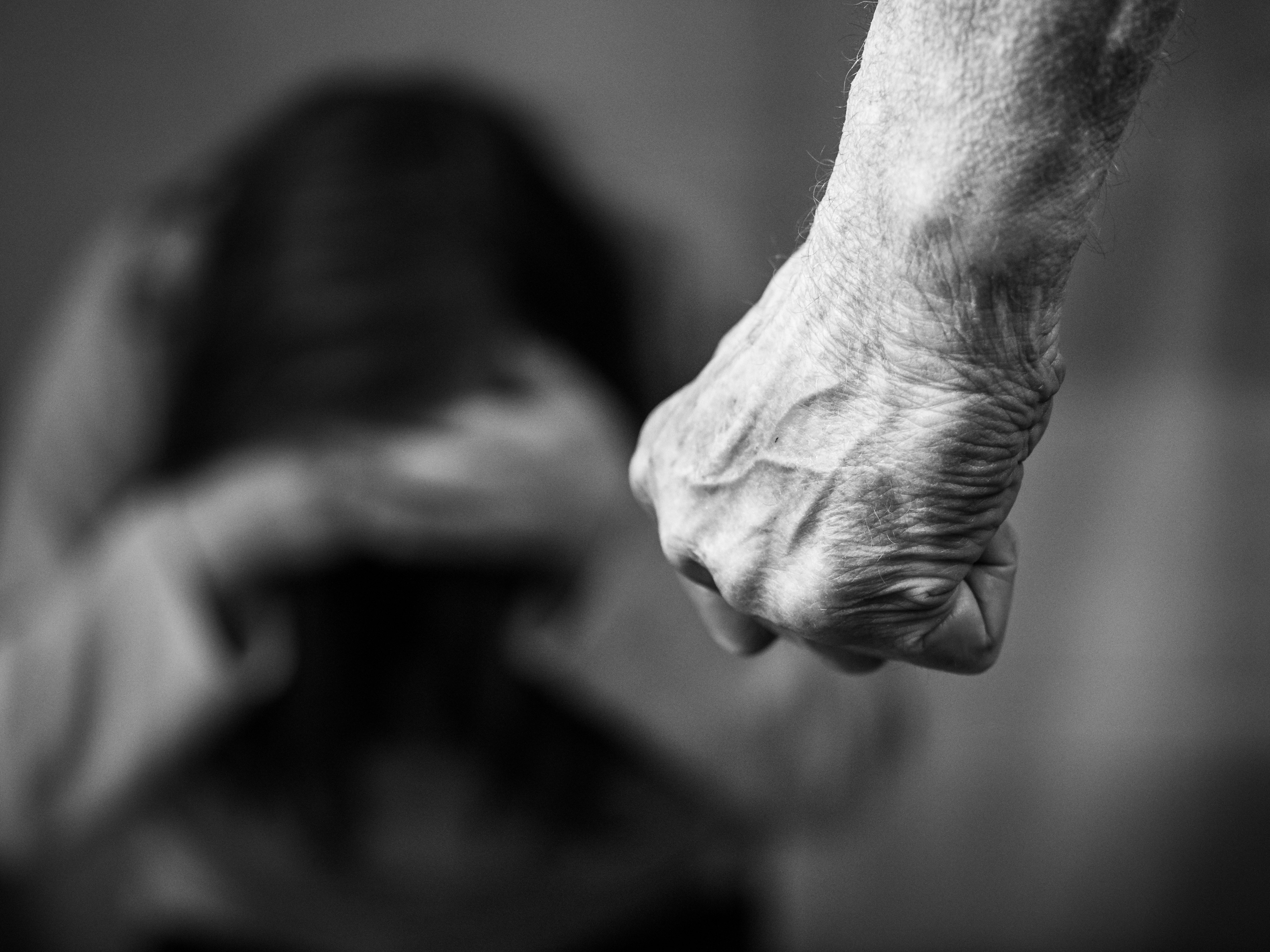Un poing serré avec une femme effrayée en arrière-plan | Source : Shutterstock