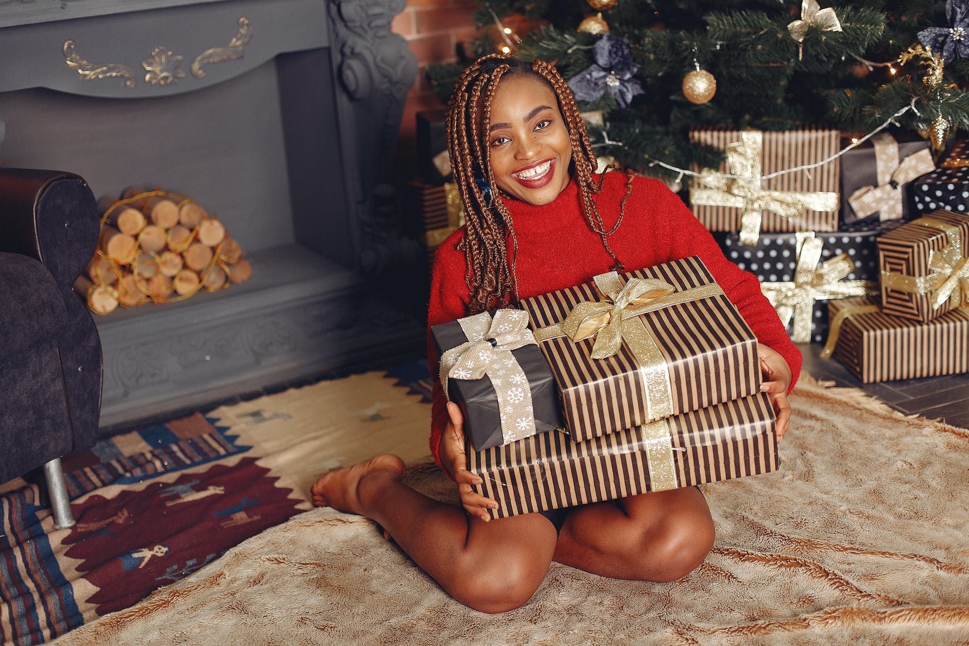 Une femme noire souriante tenant des paquets cadeaux | Source : Pexels