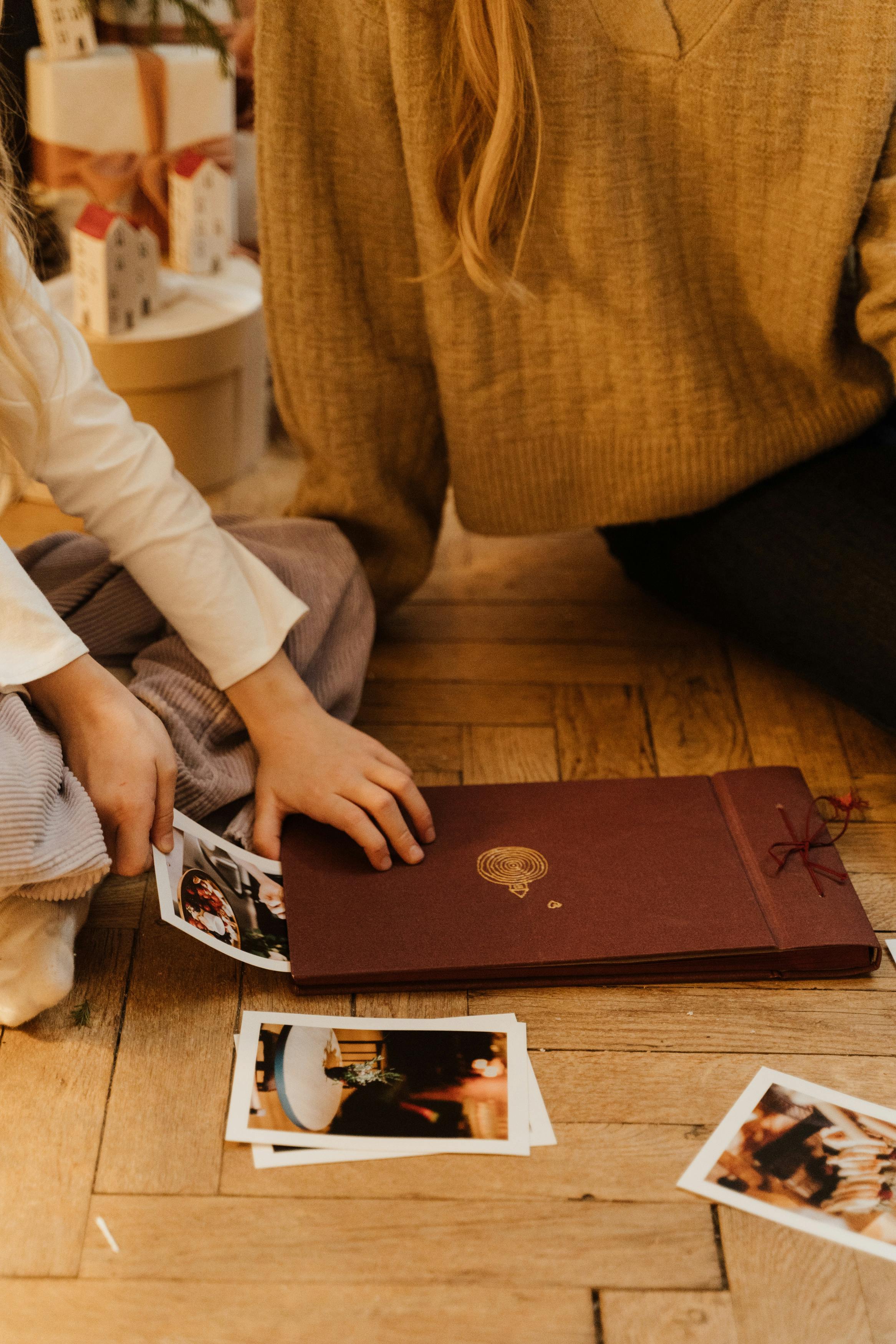 Un enfant retire des photos d'un livre avec un adulte assis à ses côtés | Source : Pexels