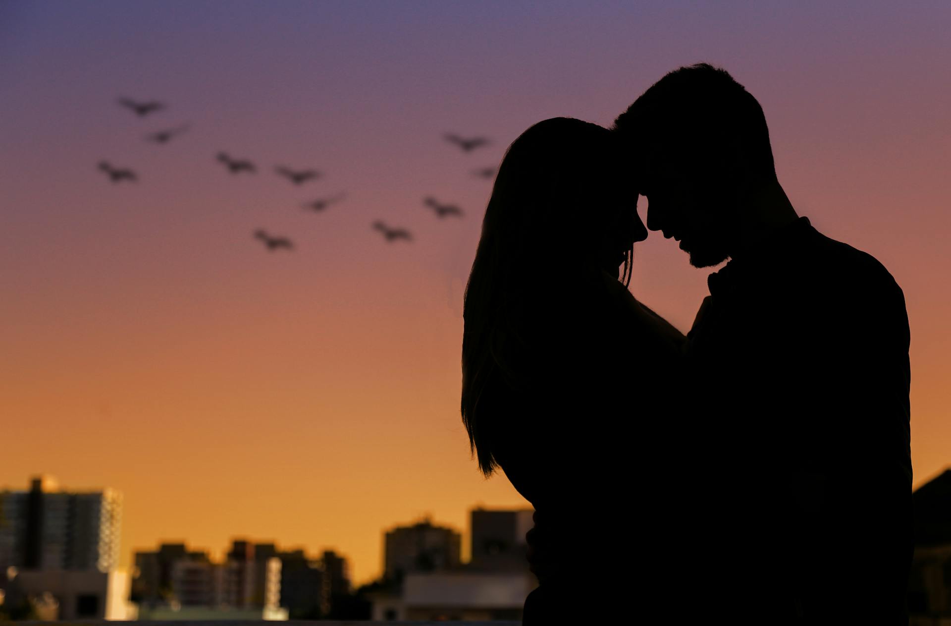 Un couple se détachant sur la ligne d'horizon d'une ville au coucher du soleil | Source : Pexels